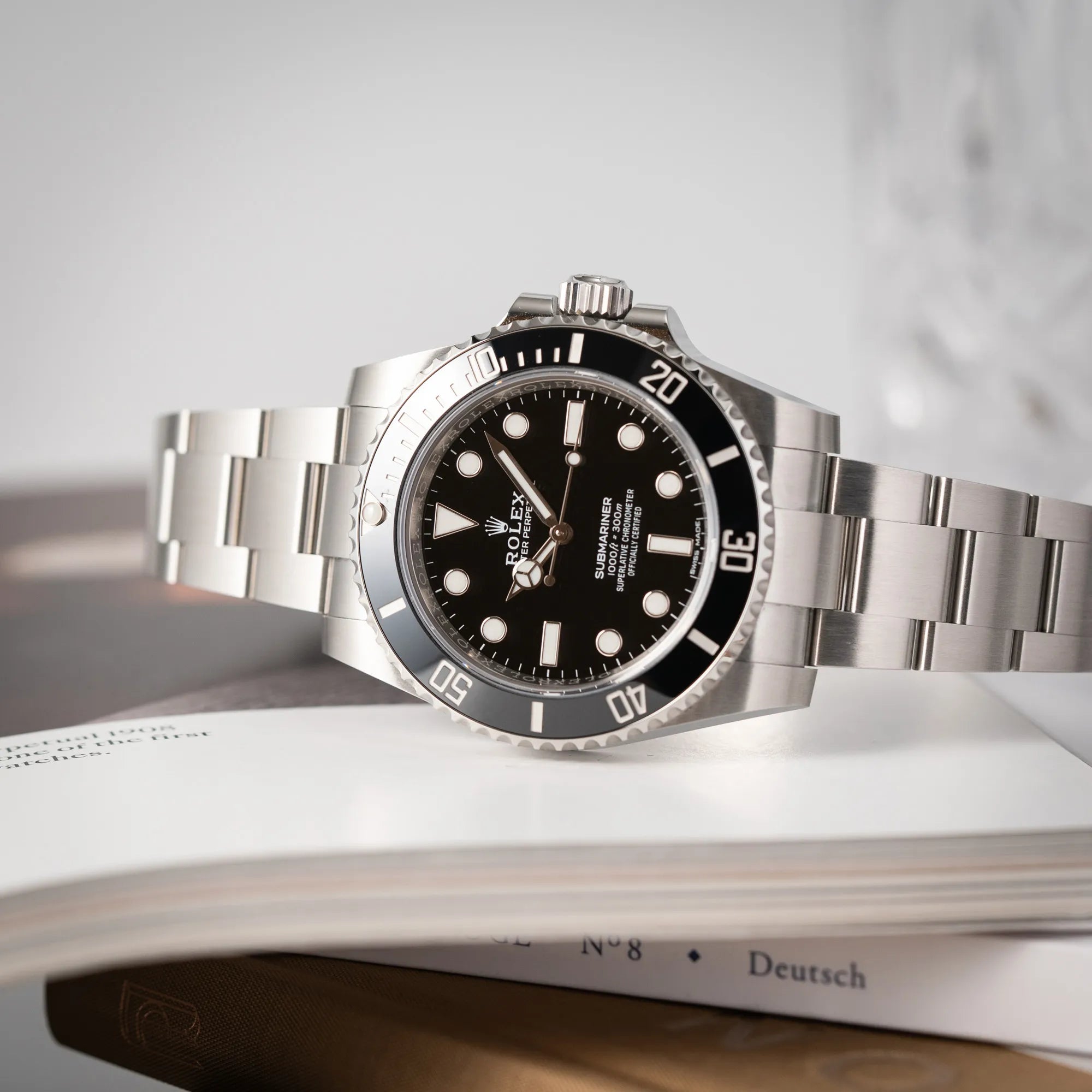 Seitlich auf dem Uhrengehäuse liegenden Rolex Submariner 114060 No Date aus 2019 in der klassischen schwarzen Ausführung im Neuzustand
