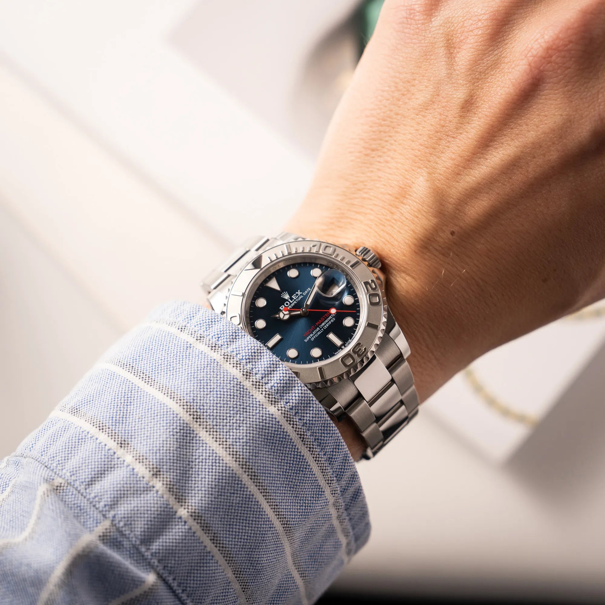 Arm eines Mannes mit hellblauen Hemd trägt die Rolex Yacht-Master 40 der Referenz 126622 mit der Platin-Lünette in der blauen Zifferblatt-Variante an seinem Handgelenk