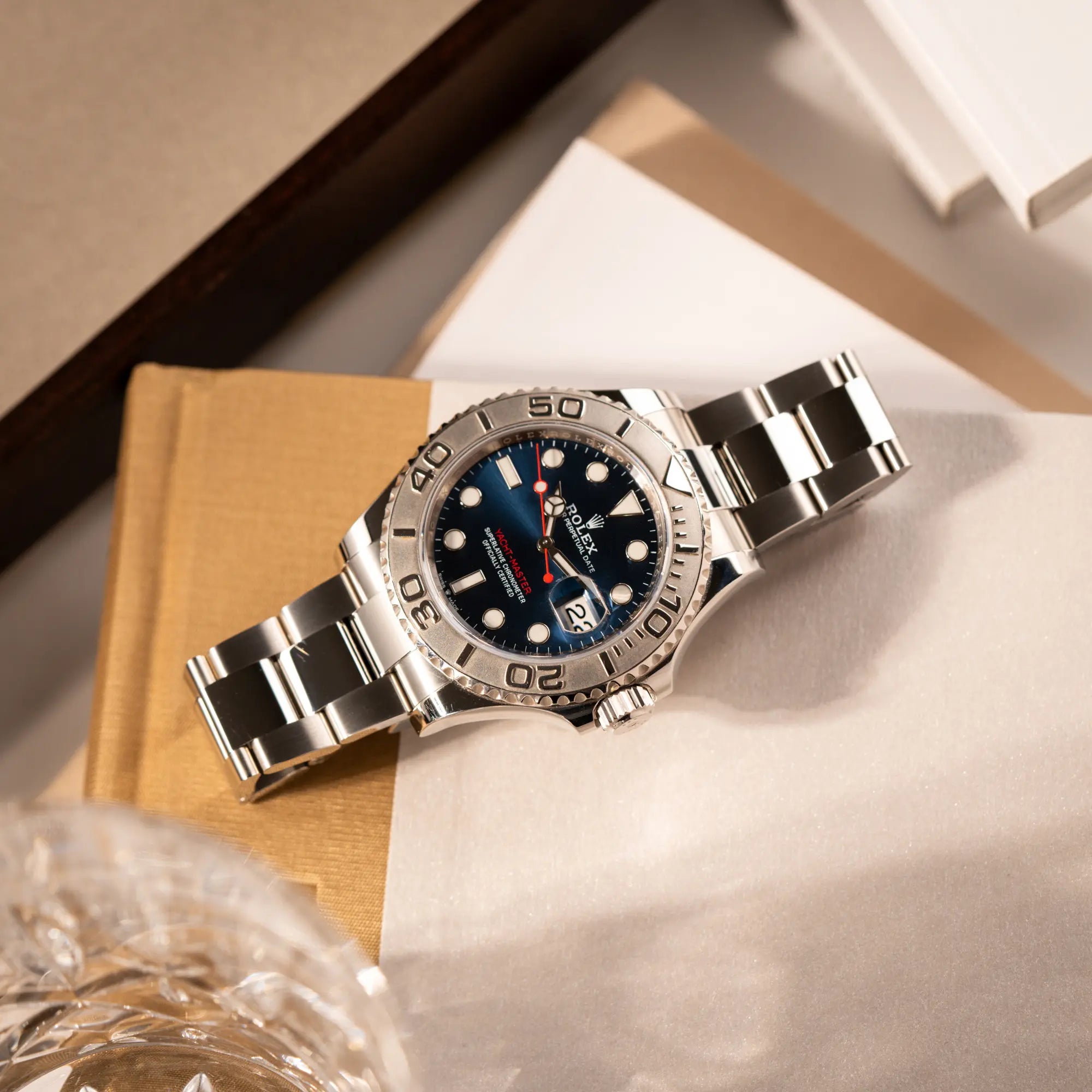 Produktfoto der Rolex Yachtmaster 40 der Referenz 126622 mit blauem Zifferblatt und der Rolesium-Lünette aus Platin, die auf einem Juwelierstablet liegt