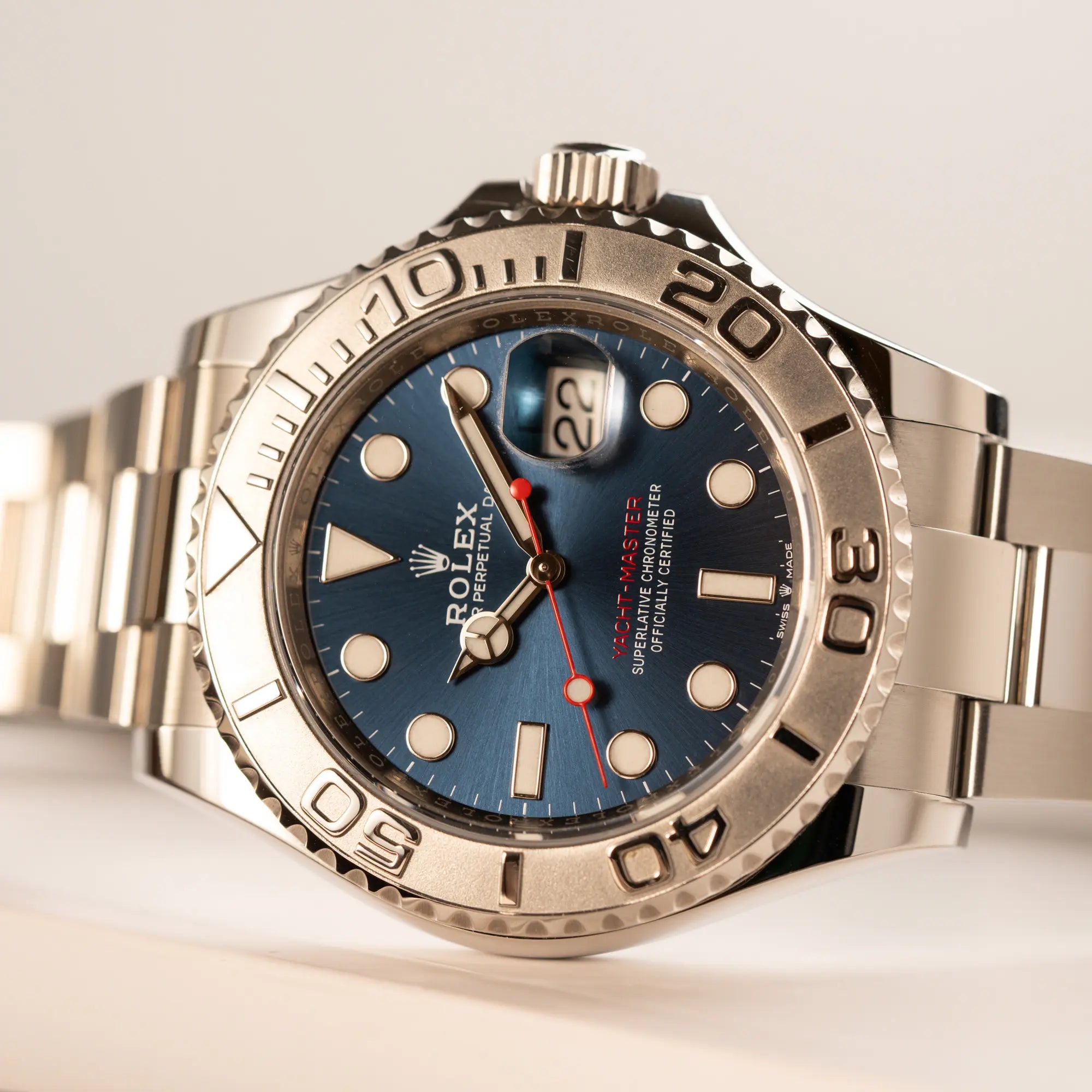 Rolex Yachtmaster 40 der Referenz 126622 mit blauem Zifferblatt und der Rolesium-Lünette aus Platin liegt seitlich auf dem Uhrengehäuse