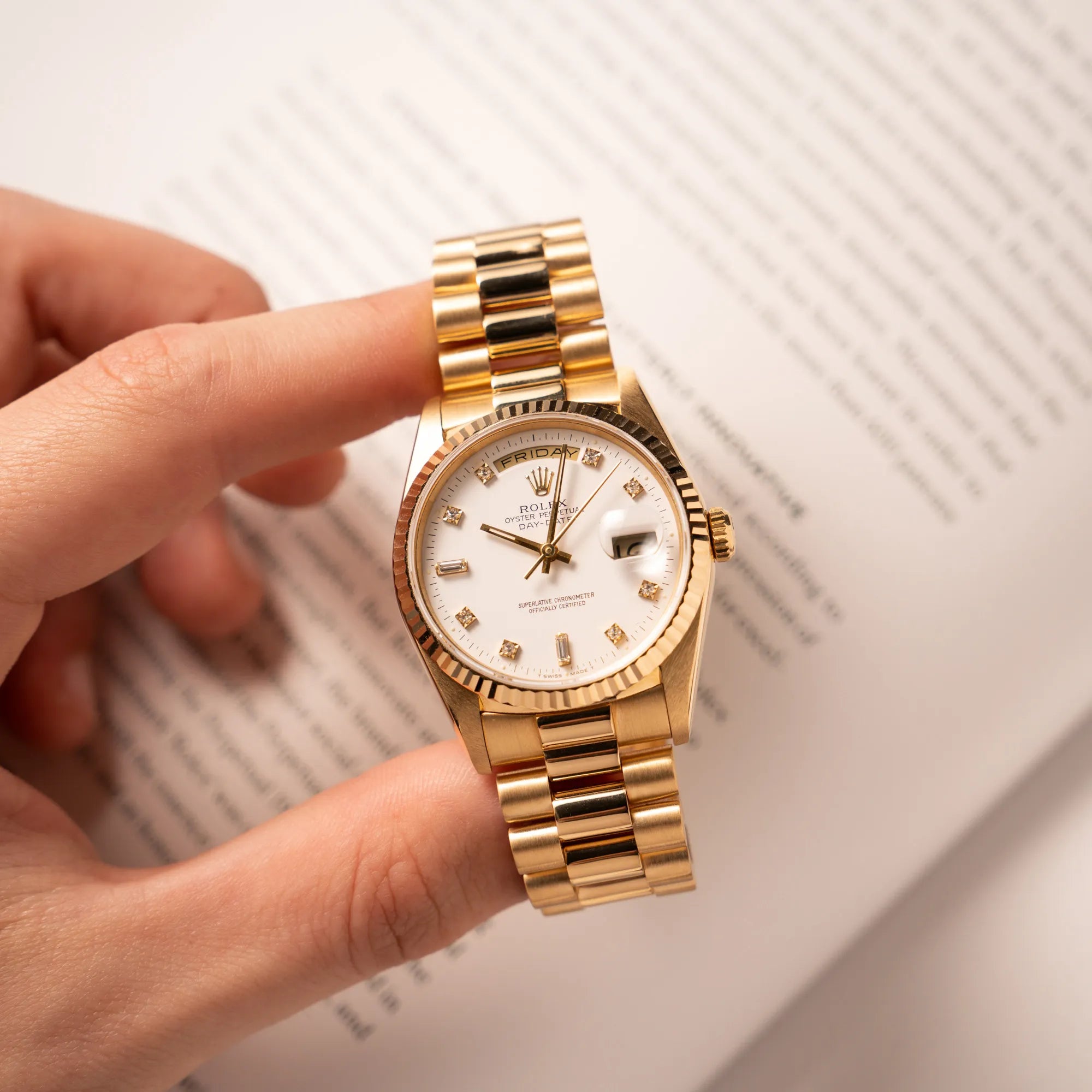 Mann hält die Rolex Day-Date 36 der Referenz 18238 in Gelbgold mit weißem Diamant-Zifferblatt in seiner Hand