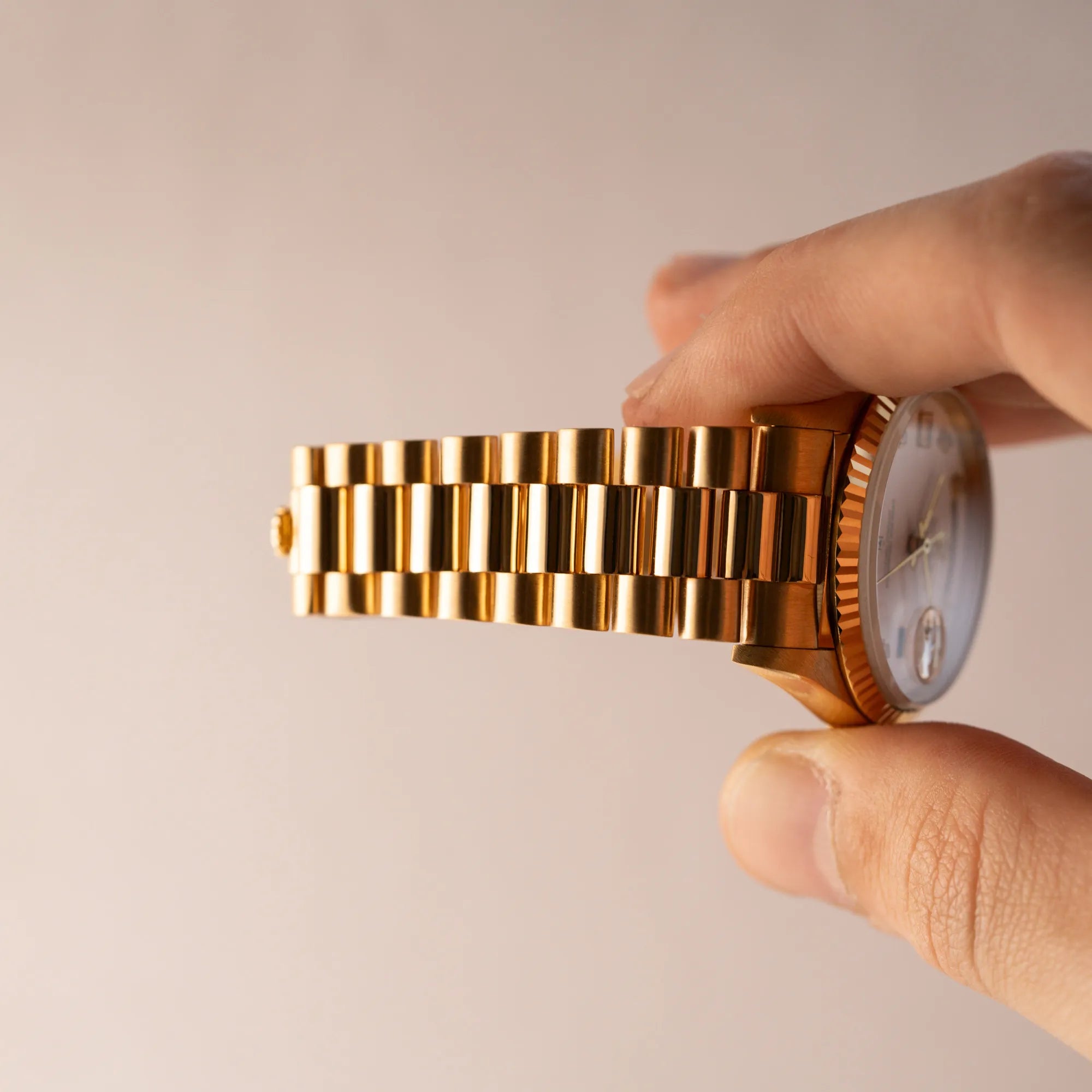 Mann hält die Rolex Day-Date 36 der Referenz 18238 in Gelbgold mit weißem Diamant-Zifferblatt vertikal in der Luft und zeigt den Stretch des President-Armbands