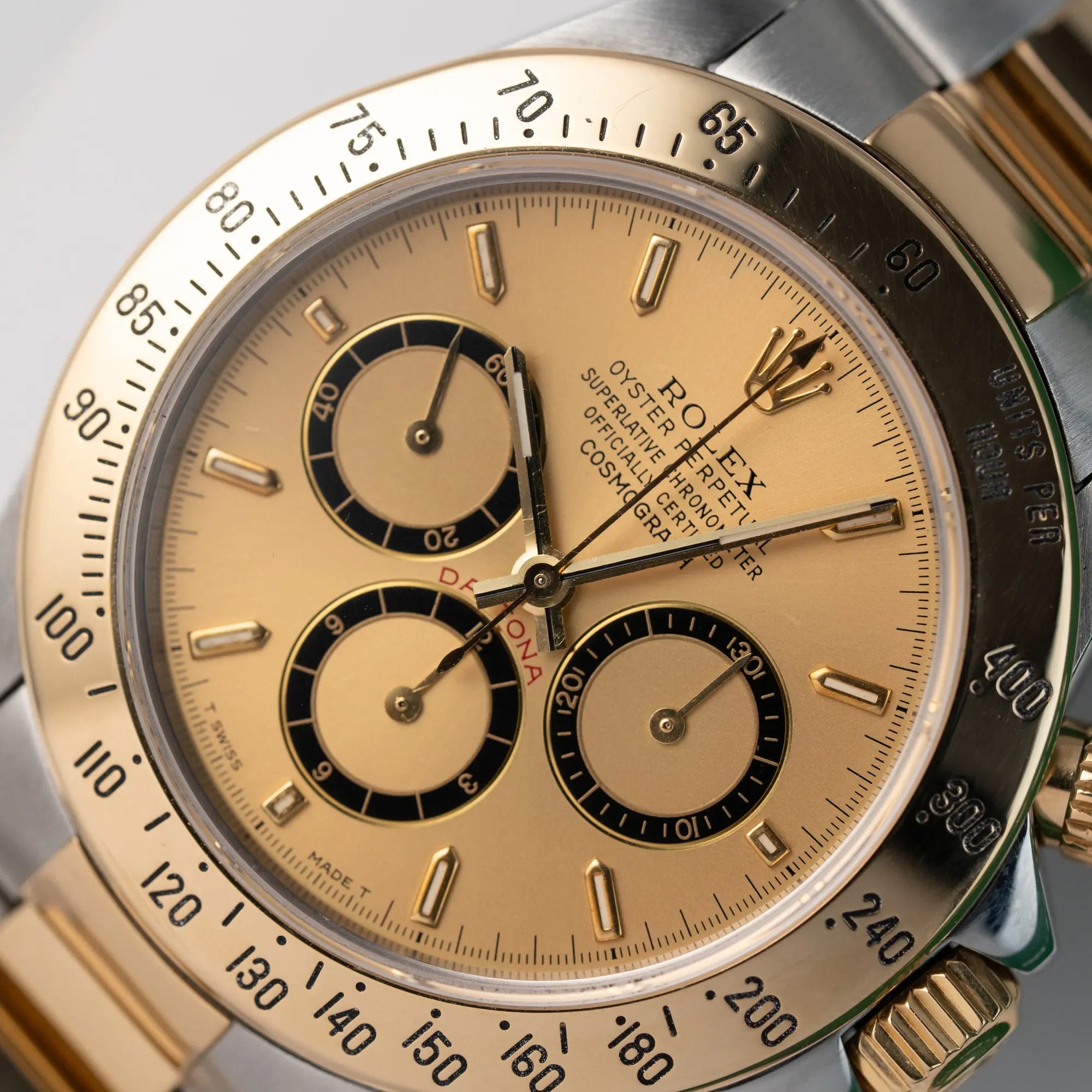 Detailaufnahme des uhrenkopfes der olex Zenith Daytona in Stahl-Gold mit goldfarbenem Zifferblatt und rotem Daytona-Schriftzug
