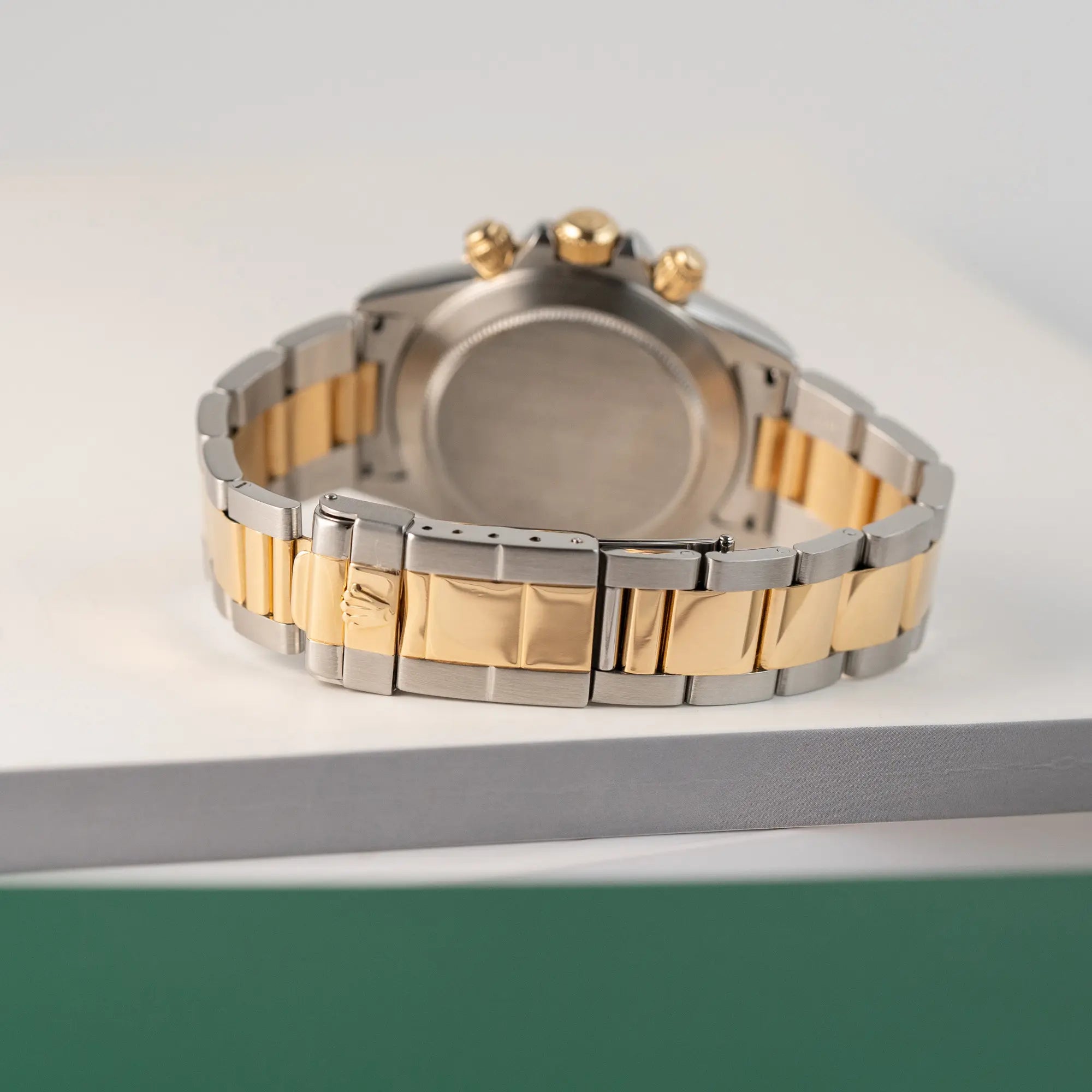 Produktfotografie der Rolex Zenith Daytona in Stahl-Gold mit goldfarbenem Zifferblatt mit Fokus auf dem Zustand des Bandes und der Oyster-Faltschliesse