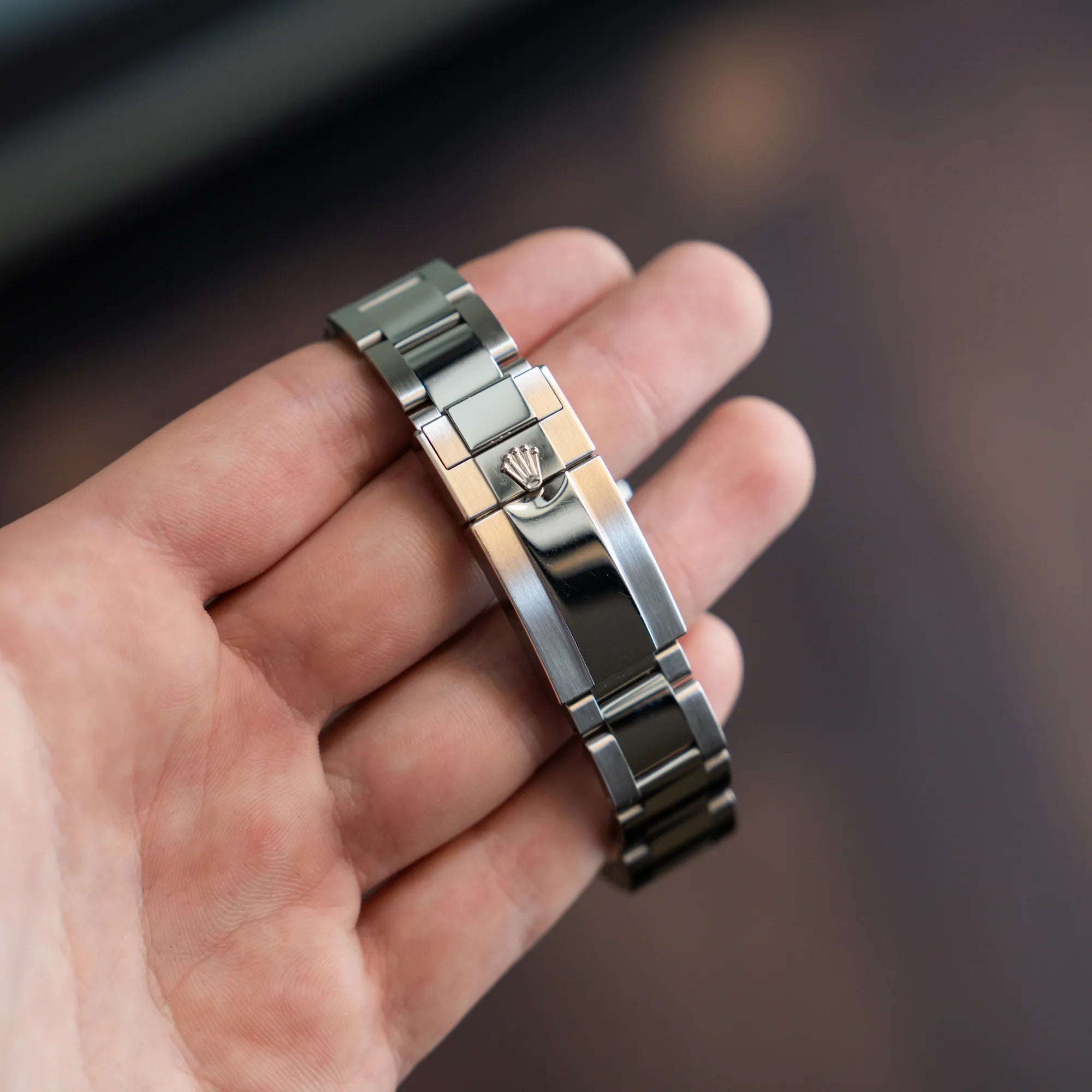 Mann hält die Rolex GMT Master 2 in Schwarz mit der Keramik-Lünette in einem neuwertigen Zustand in seiner Hand und präsentiert die Faltschliesse