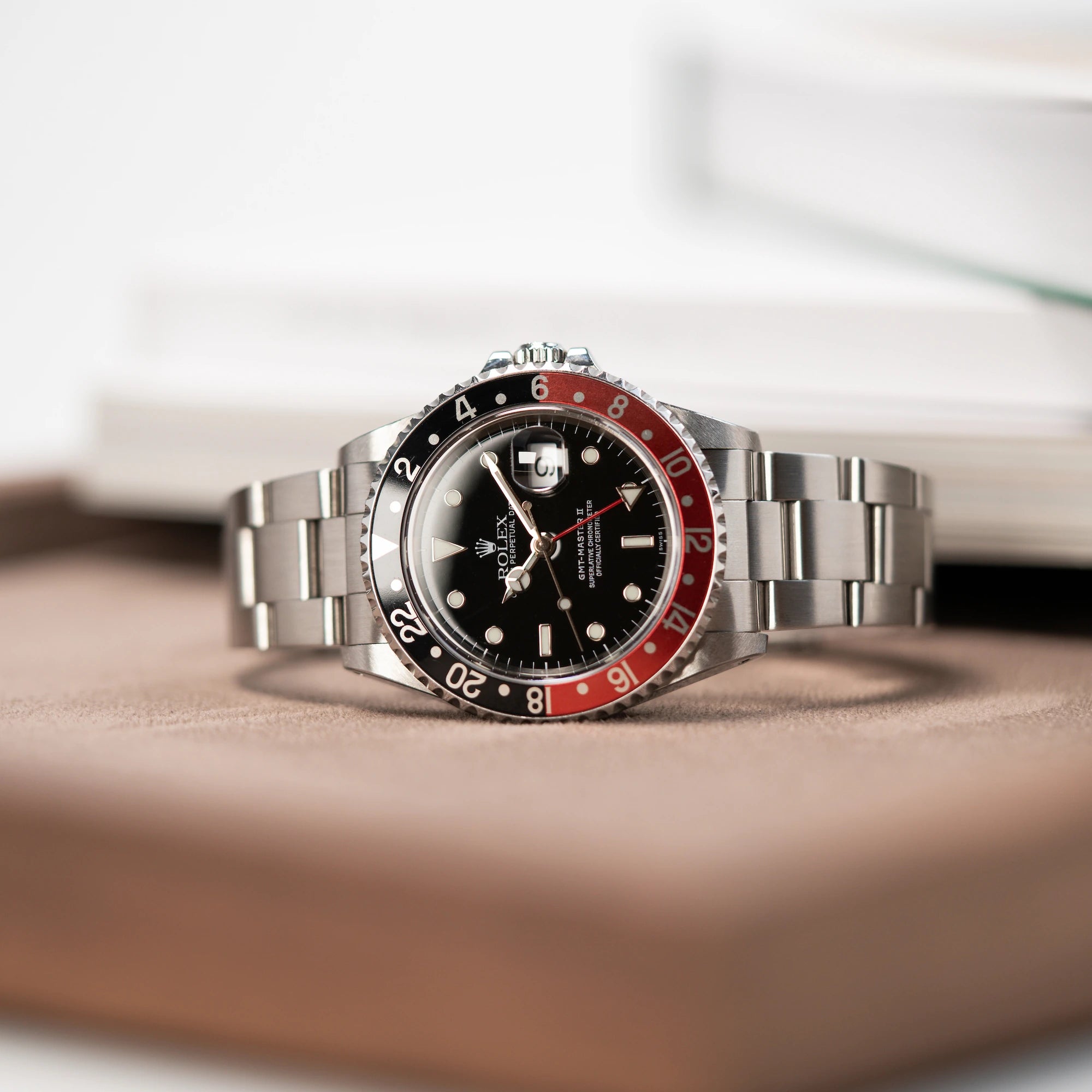 Produktfotografie der liegenden Rolex GMT Master 2 (Referenz 16710) mit der Coke-Lünette in schwarz-rot mit dem "Swiss-Only" Zifferblatt