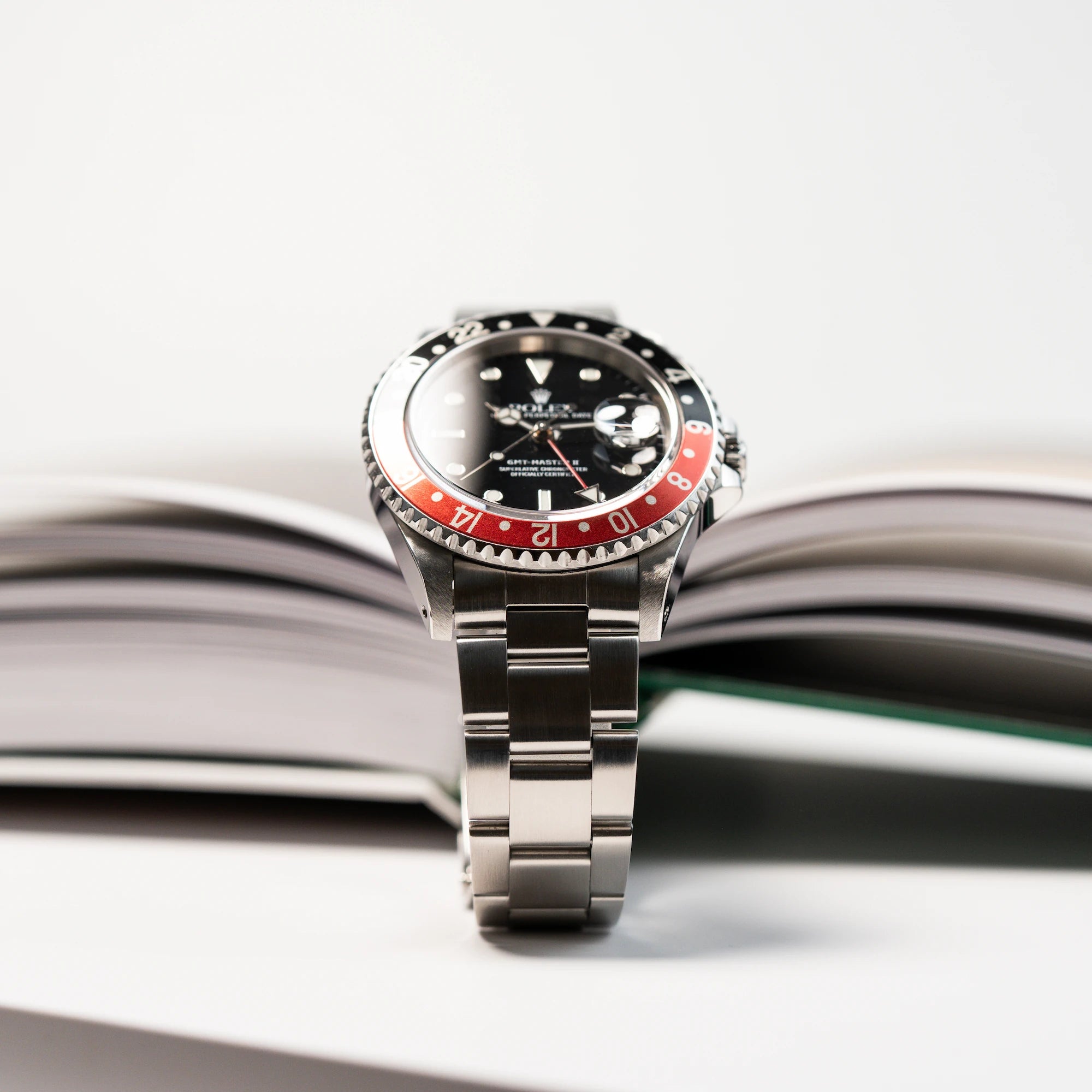 Perfekt beleuchtete Produktfotografie der Makroaufnahme des Zifferblatts und der Lünette derSeitliches Gehäuse der Rolex GMT Master 2 (Referenz 16710) mit der Coke-Lünette in schwarz-rot mit dem Swiss-Only Ziffferblatt