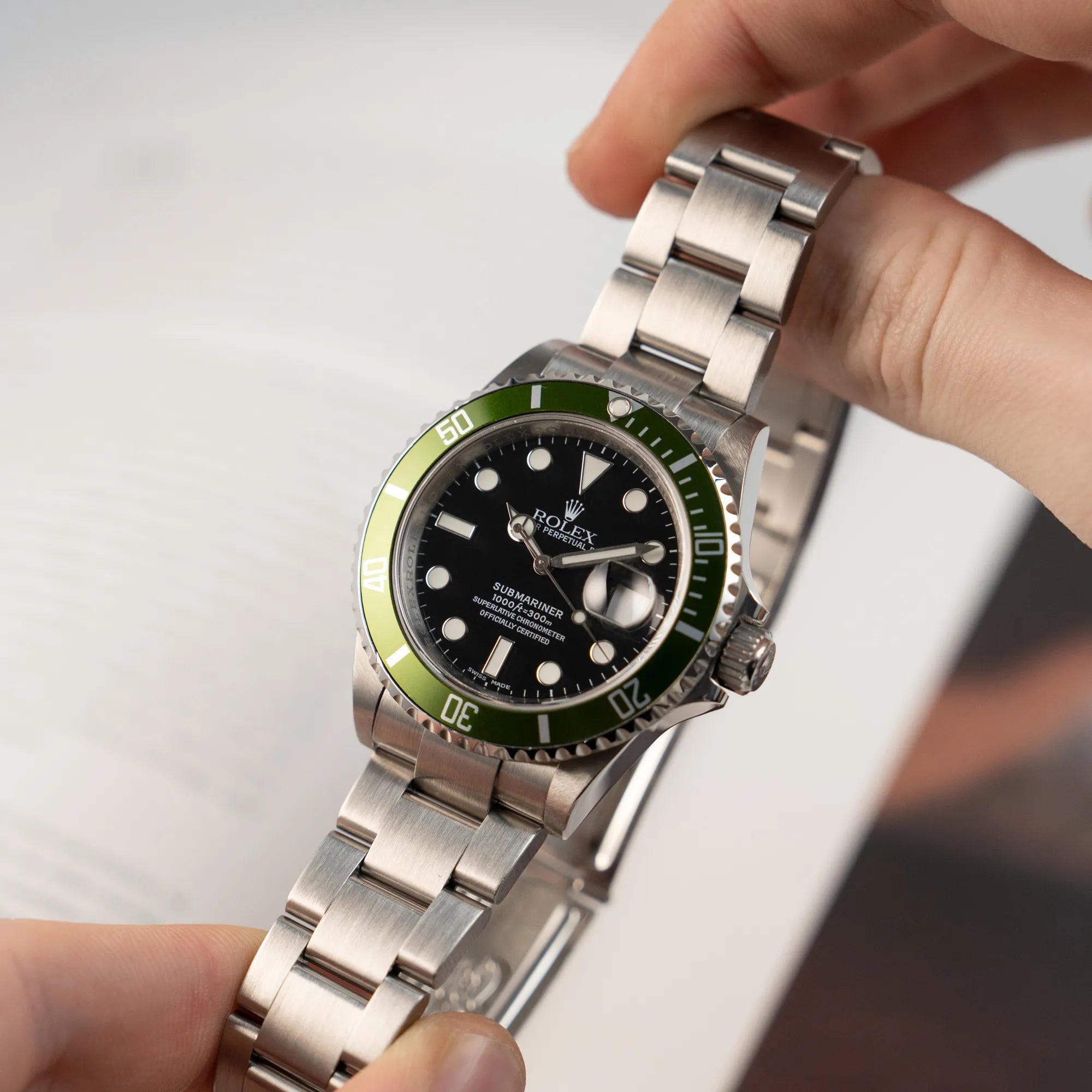 Mann präsentiert die Rolex Submariner Date Taucheruhr in der ikonischen Kermit-Variante mit einer einzigartigen Lime-Lünette