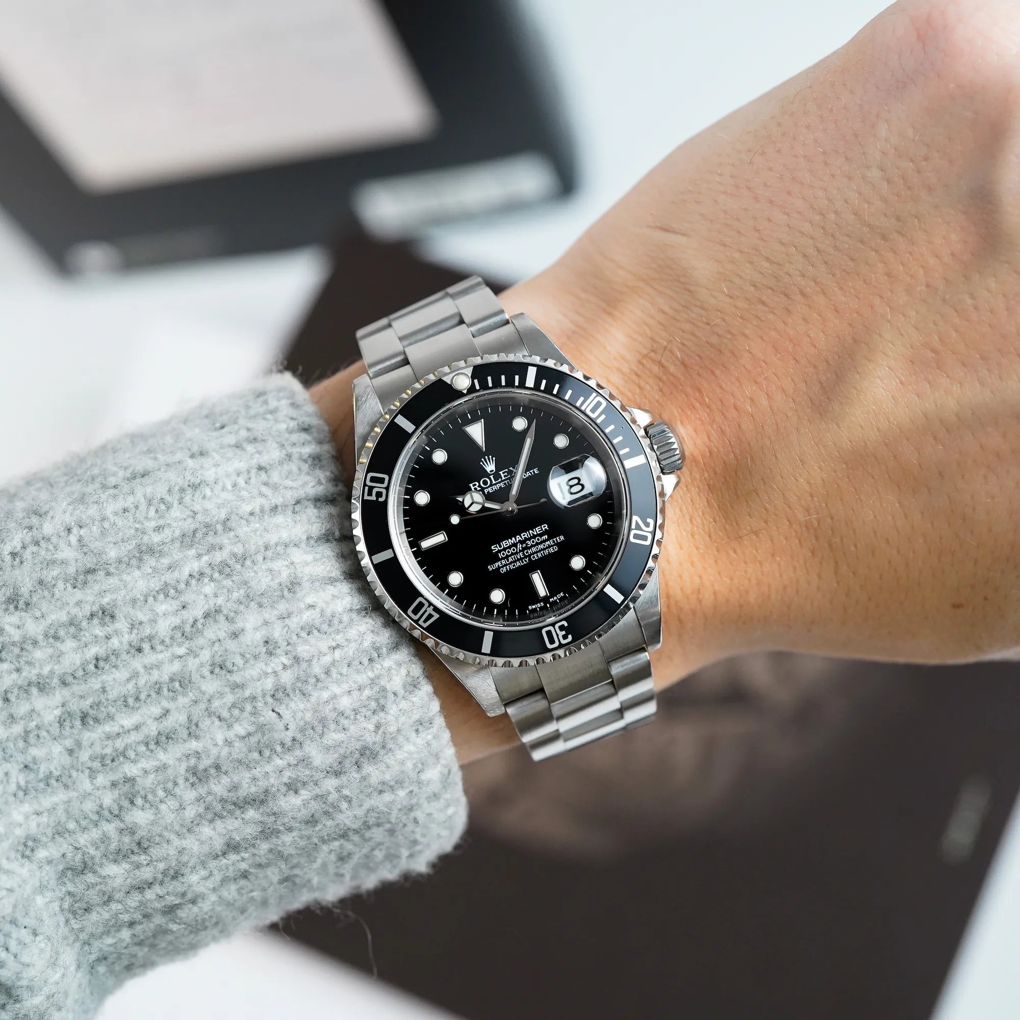 Mann trägt die Rolex Submariner Date in schwarz, Referenz 16610, mit Flat-Four-Lünette am Handgelenk