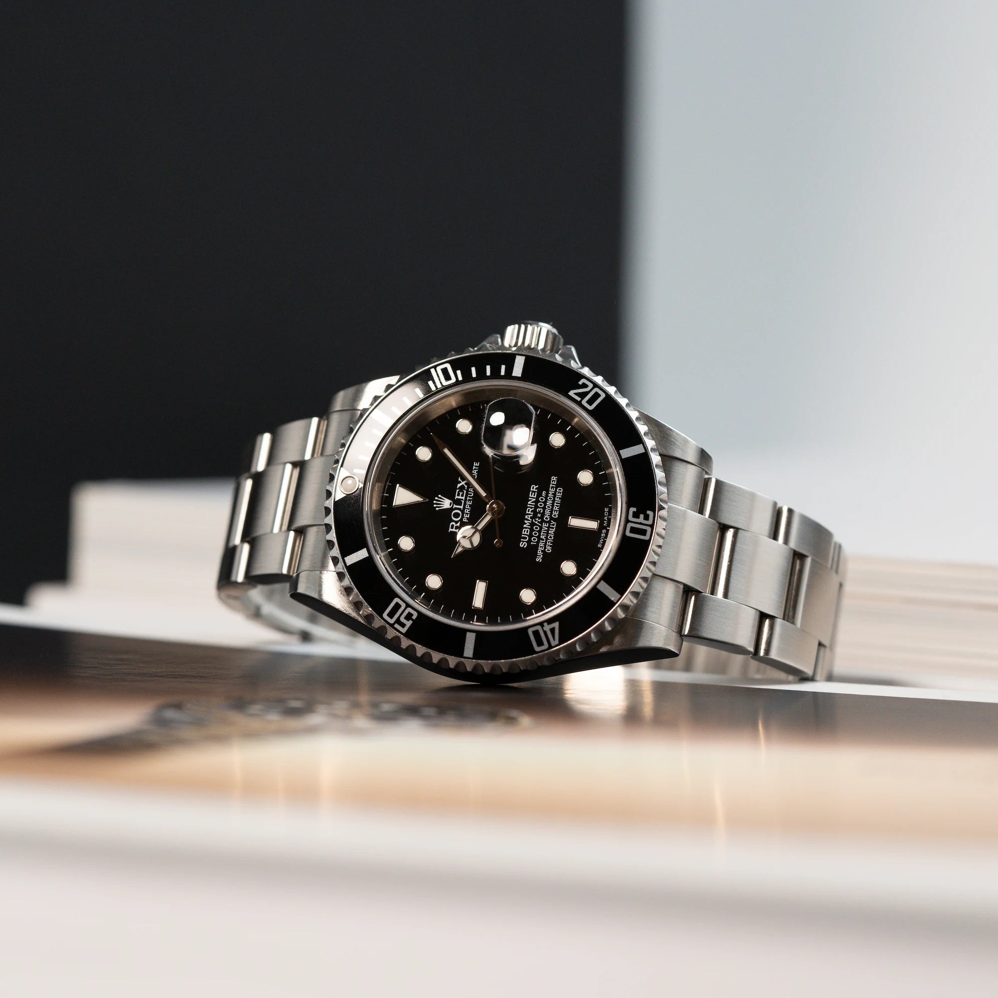 Produktfotografie der Rolex Submariner Date in Schwarz mit der Referenz 16610T, die auf einem Buch liegt