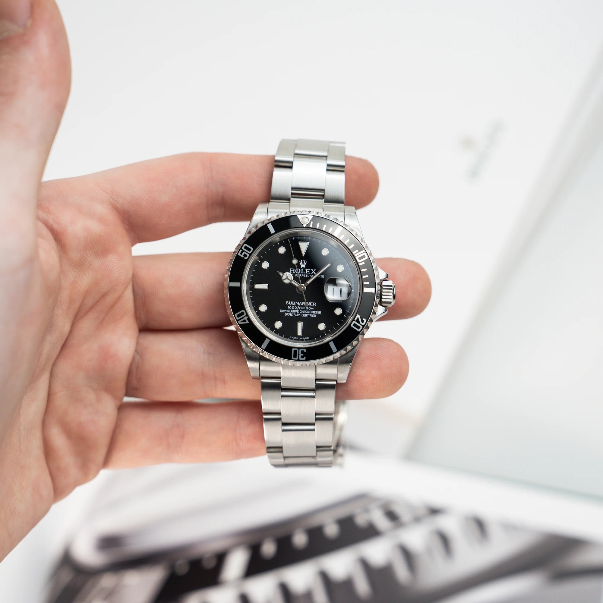 Mann hält die Rolex Submariner Date in Schwarz mit der Referenz 16610T in seiner Hand