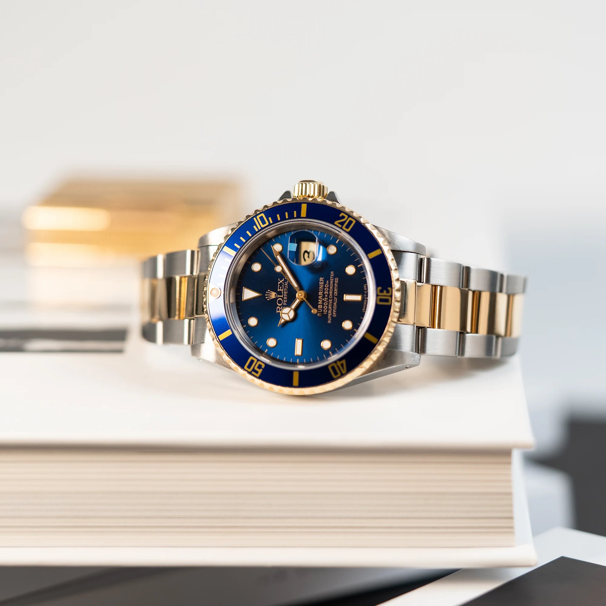 Produktfotografie der mit blauem Zifferblatt und Lünette, während die Uhr auf einem Buch liegt