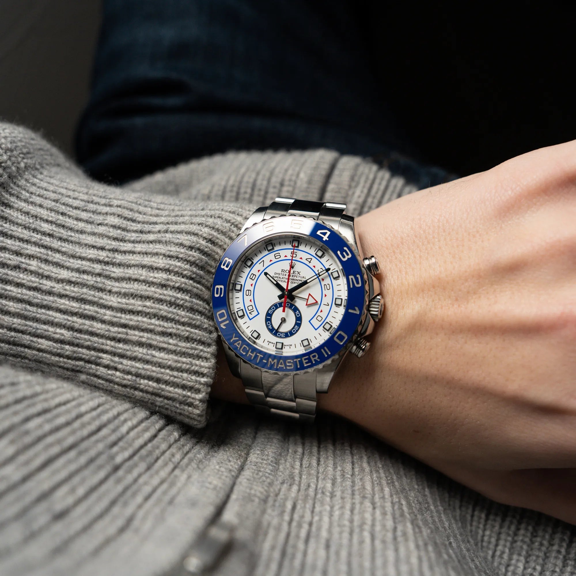 Mann in grauem Strickpullover trägt die Rolex Yacht-Master 2 mit weißem Zifferblatt und blauer Lynette an seinem Handgelenk