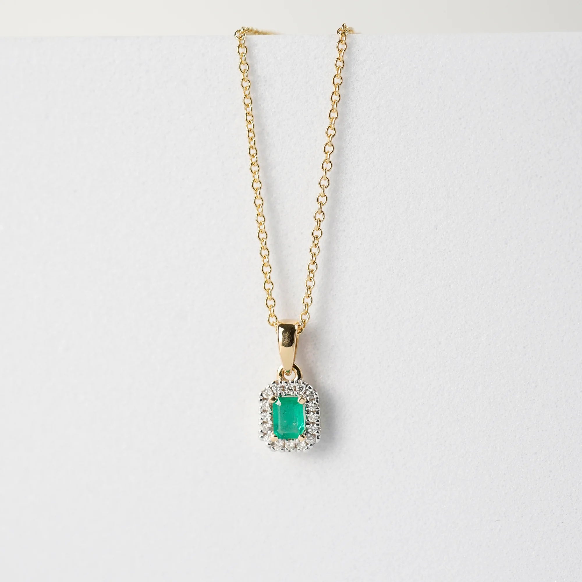 Produktfoto des Anhängers mit einem zentralen Smaragd mit einer kräftigen grünen Farbe, der von kleinen Diamanten umrandet ist, von der Smaragd-Brillant-Kette aus der Schmuckatelier Lang Collection zusammen mit der gelbgoldenen Kette