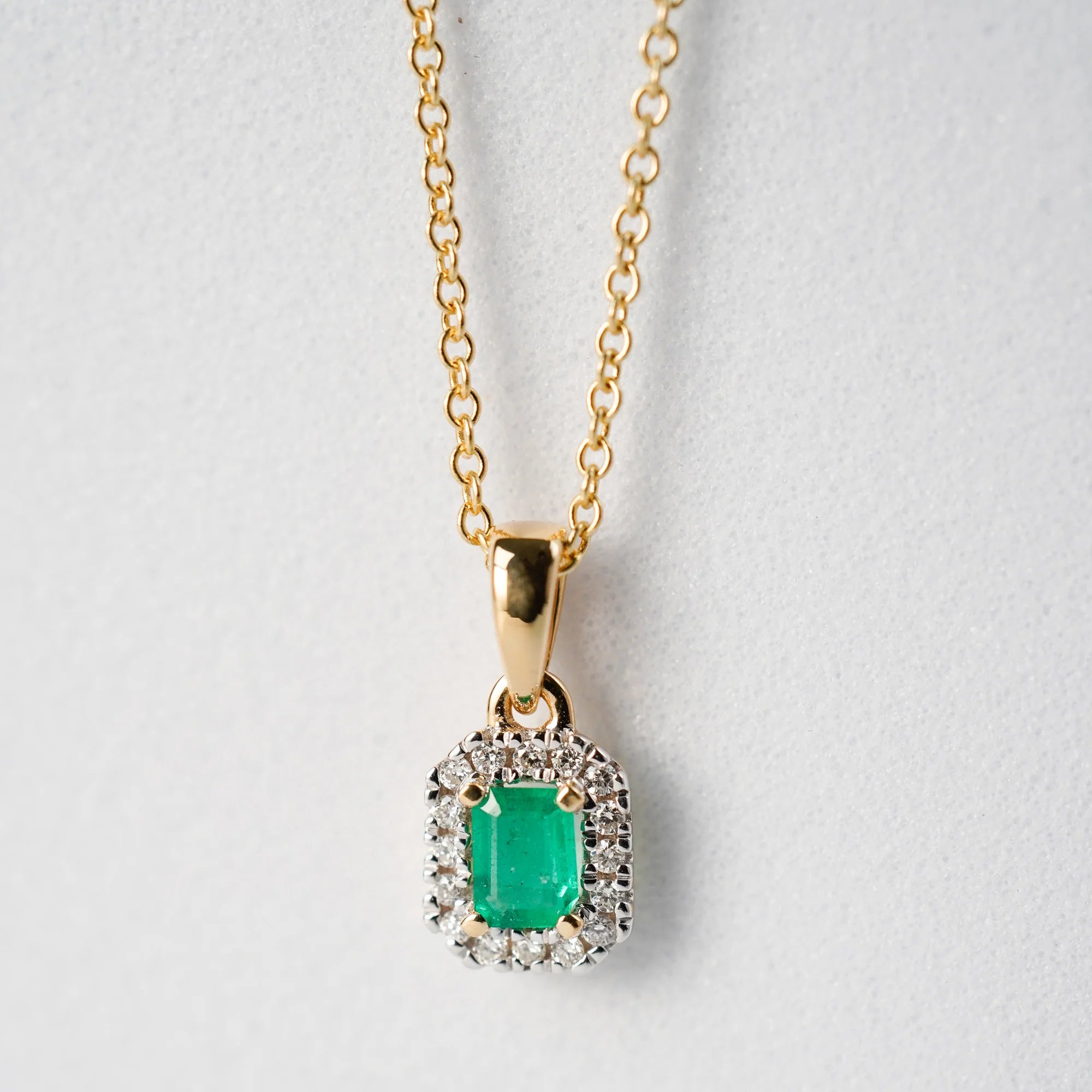 Produktfoto des Anhängers mit einem zentralen Smaragd mit einer kräftigen grünen Farbe, der von kleinen Diamanten umrandet ist, von der Smaragd-Brillant-Kette aus der Schmuckatelier Lang Collection
