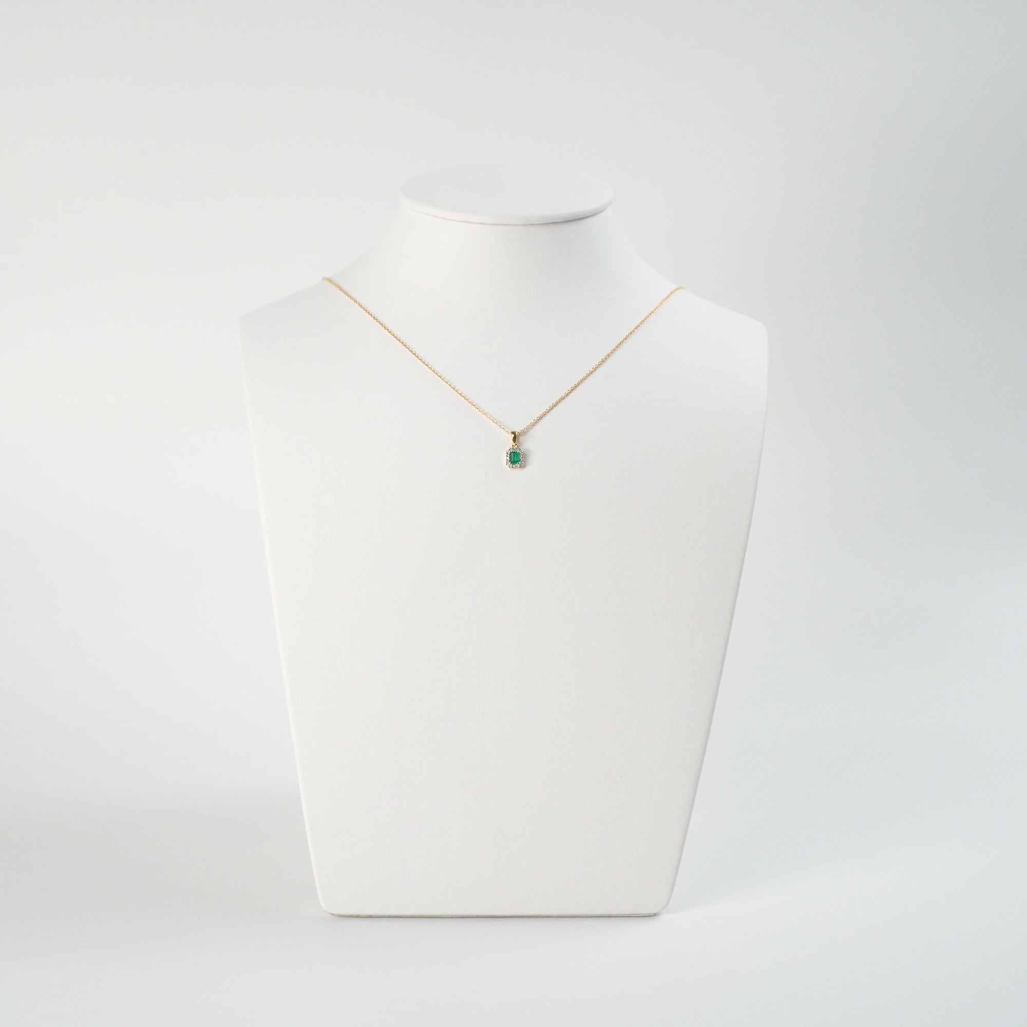 Smaragd Brillant Kette, bestehend aus einem Smaragd-Brillant Anhänger mit goldener Öse und einer goldenen feinen Kette aus der Schmuckatelier Lang Collection wird auf einer Büste präsentiert