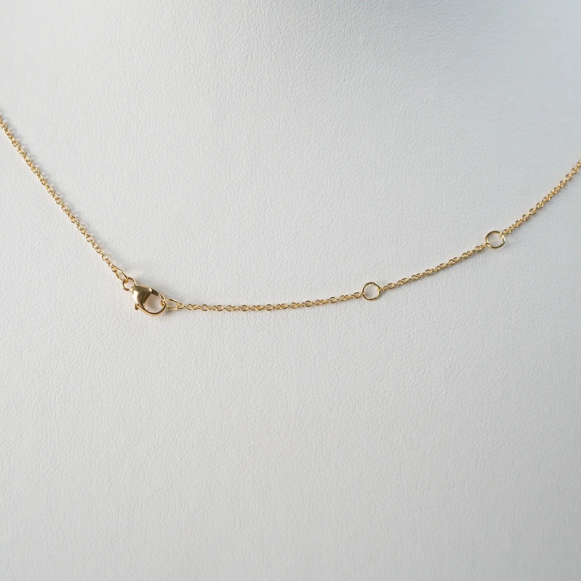 Detailaufnahme der gelbgoldenen Kette und deren Verschlussmechanismus, bestehend aus einem Karabiner und drei eingearbeiteten Ösen in der Kette, um die Länge in drei Einstellungen variieren kann