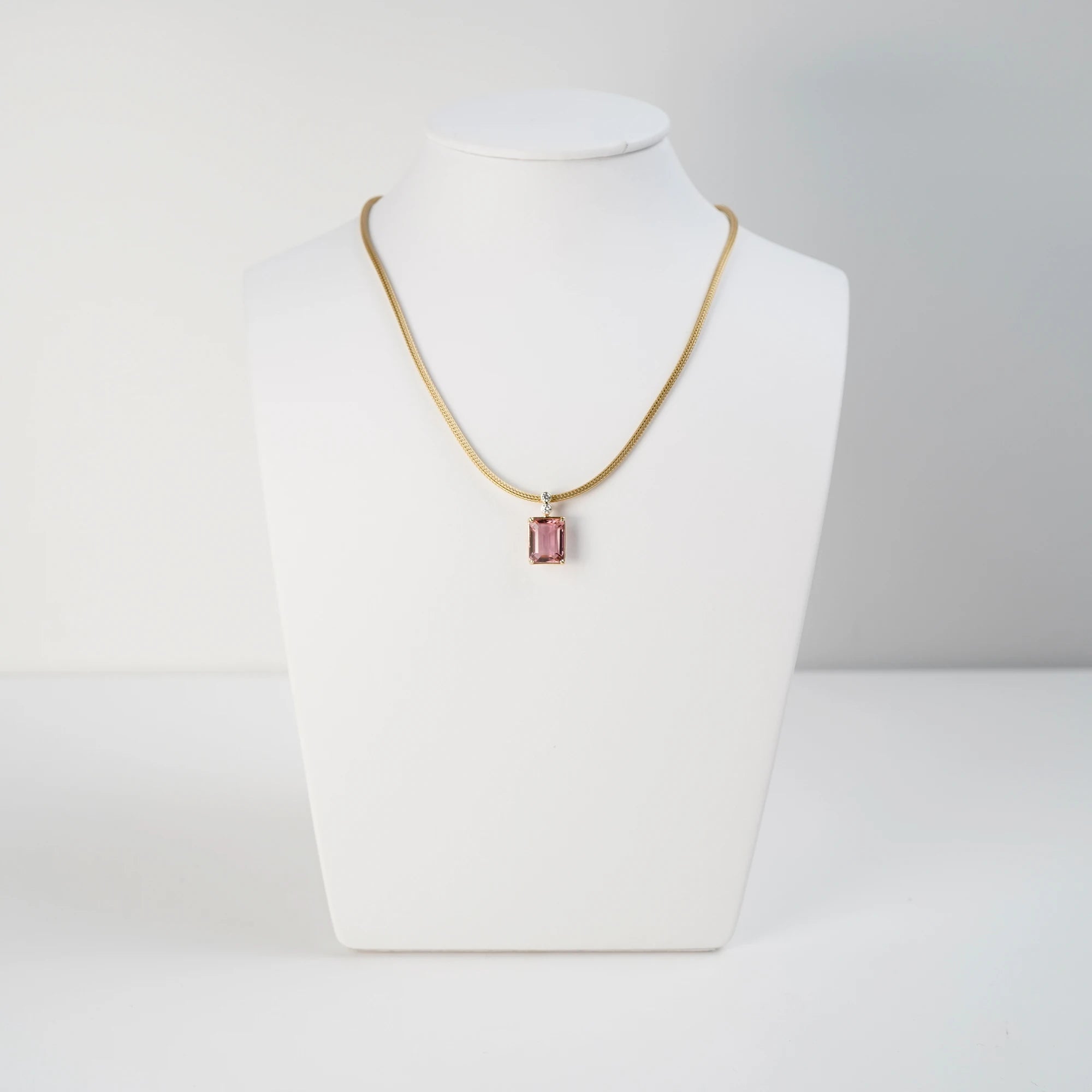 Produktfoto des gelbgoldenen Colliers aus der Schmuckatelier Lang Collection mit einem großen pinken Tansanit als Anhänger, das über eine Schmuckbüste gelegt wurde