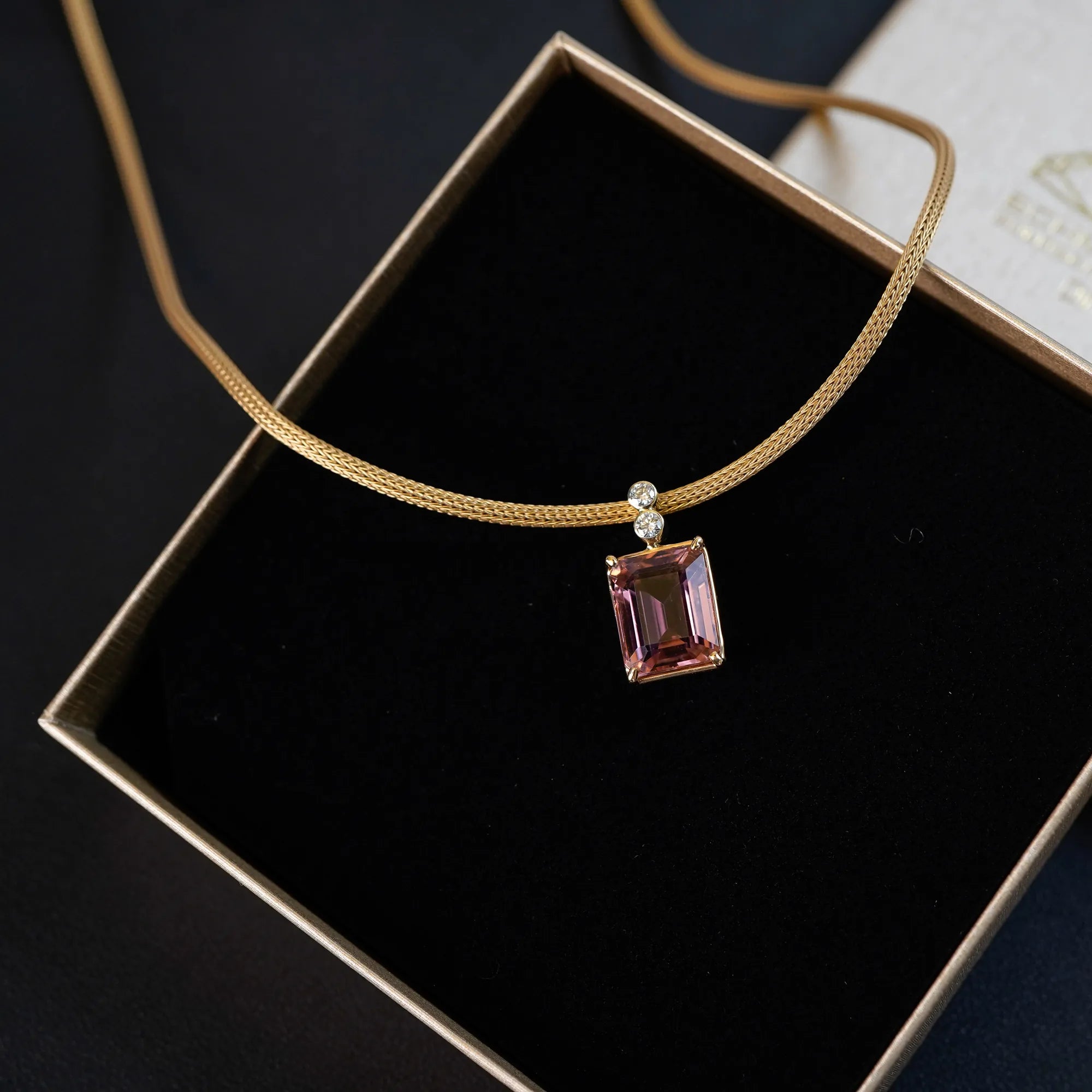 Gelbgoldenes Colliers aus der Schmuckatelier Lang Collection mit einem großen pinken Tansanit als Anhänger, das in der Umverpackung ohne Deckel liegt