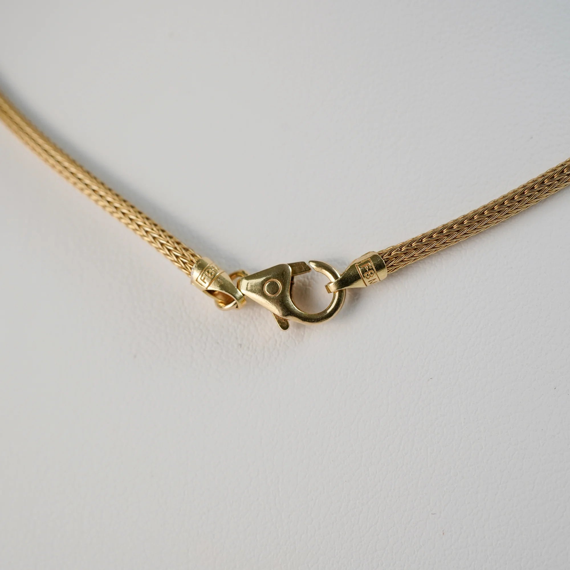 Detailaufnahme des gelbgoldenen Verschlussmechanismus mit einem Karabinerhaken