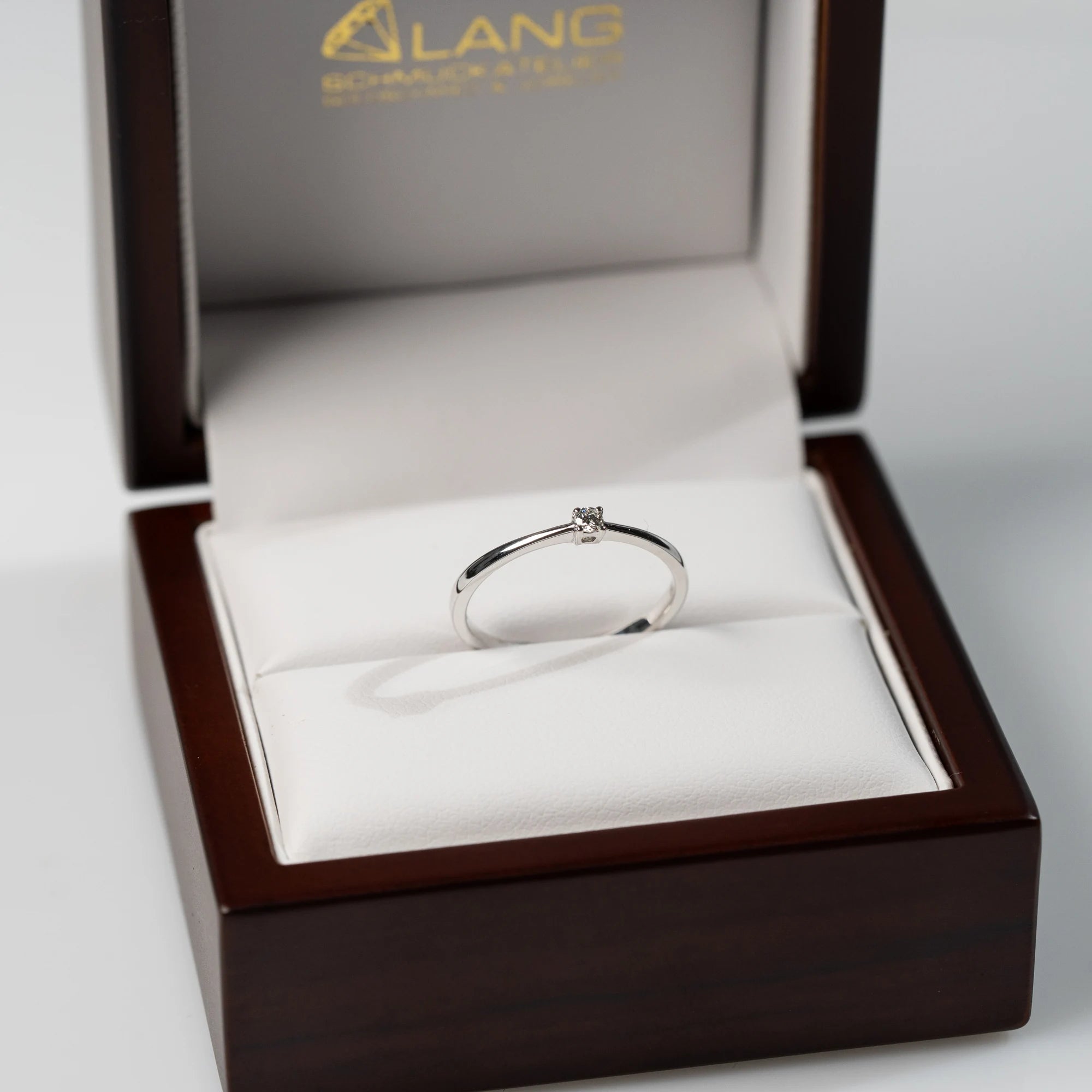 Verlobungsring "Forever" aus der Schmuckatelier Lang Collection mit einem in einer 4er Kappe gefassten Diamanten mit einem Gewicht von 0.05 Carat steckt in der hölzernen Schmuck-Box