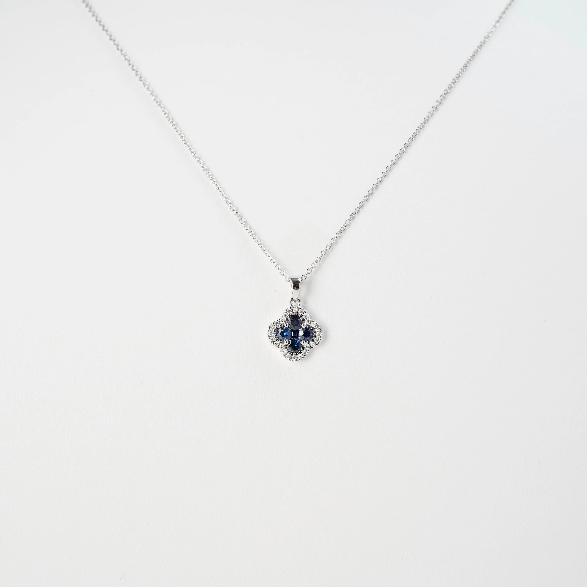 Frontale Ansicht der Saphir Kleeblatt Kette aus Weißgold mit einem Saphir-Brillant-Anhänger in einer Kleeblatt-Form, bei dem die Saphire durch die kleinen Diamanten umrandet sind