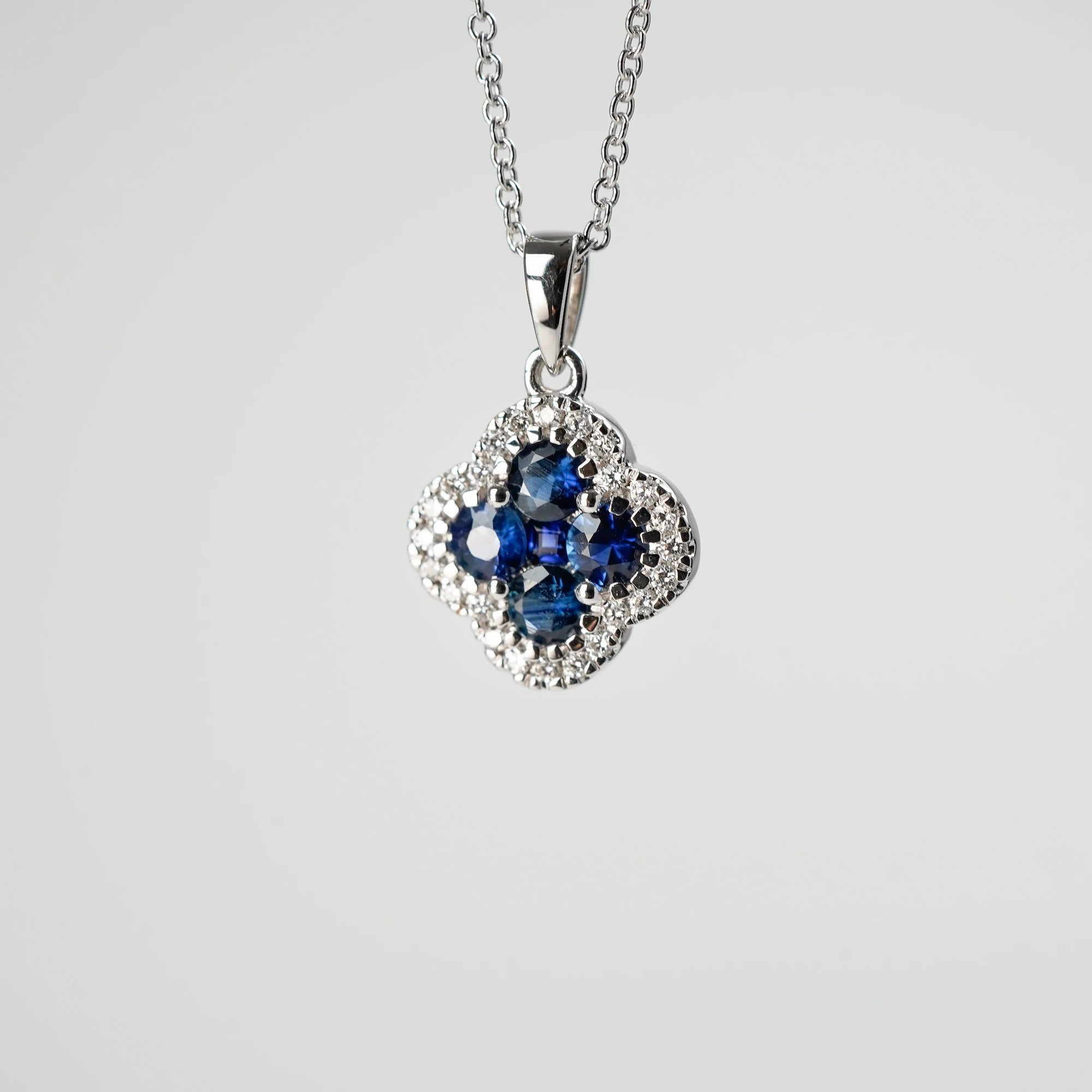 Detailaufnahme des Anhängers der Saphir Kleeblatt Kette aus Weißgold mit einem Saphir-Brillant-Anhänger in einer Kleeblatt-Form, bei dem die Saphire durch die kleinen Diamanten umrandet sind