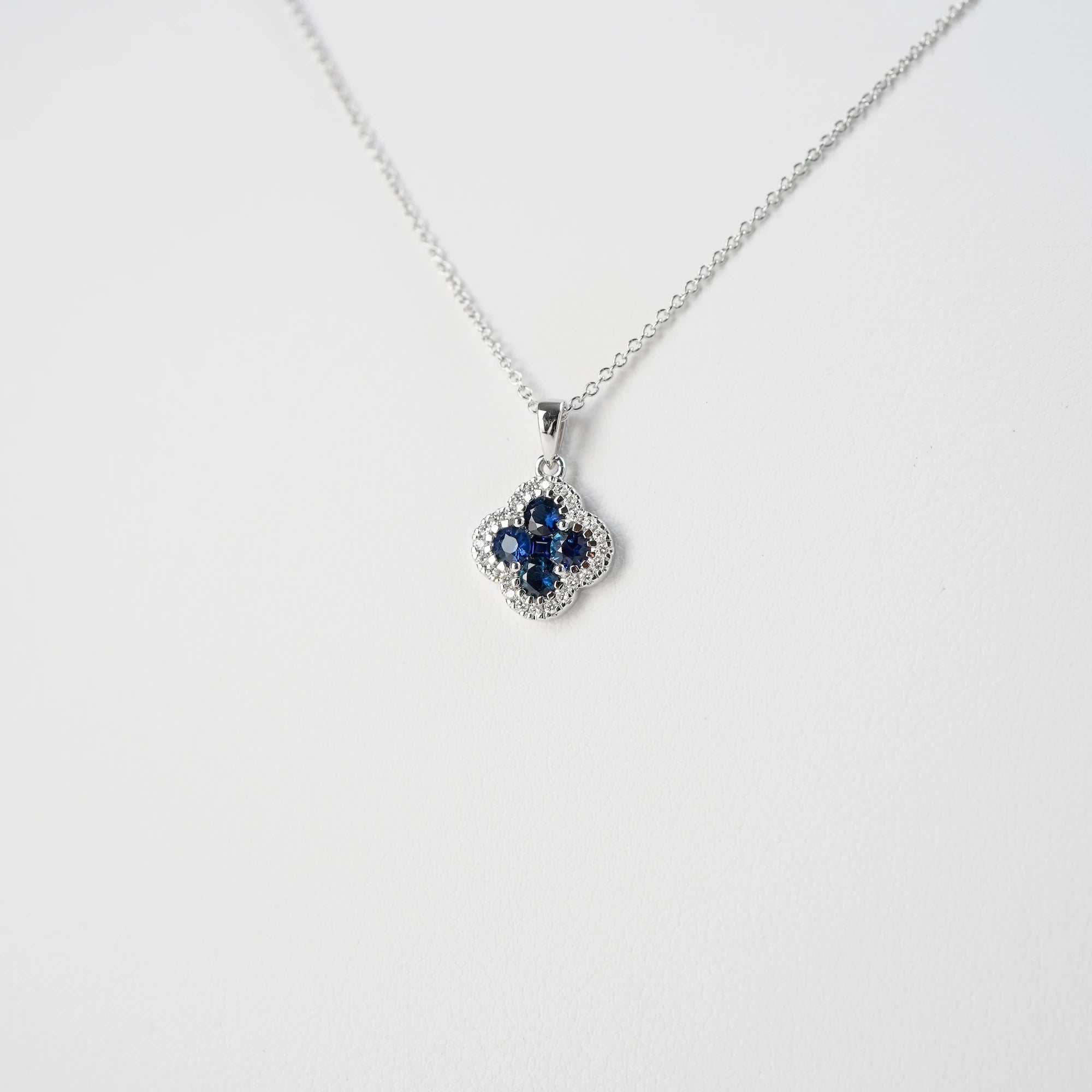 Detailaufnahme der Saphir Kleeblatt Kette aus Weißgold mit einem Saphir-Brillant-Anhänger in einer Kleeblatt-Form, bei dem die Saphire durch die kleinen Diamanten umrandet sind
