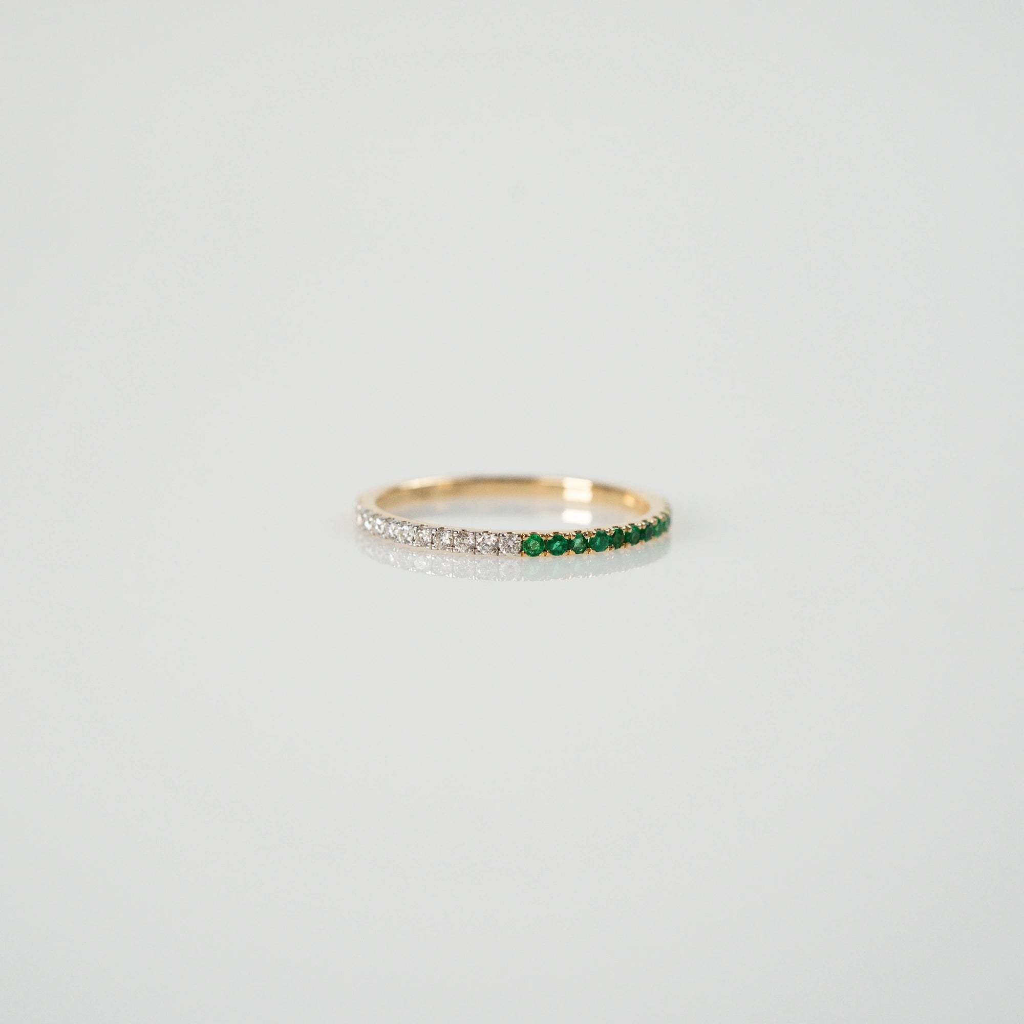 Produktfoto des liegenden Memoire Rings aus der Schmuckatelier Lang Collection, der halb mit Smaragden und halb mit Diamanten besetzt ist