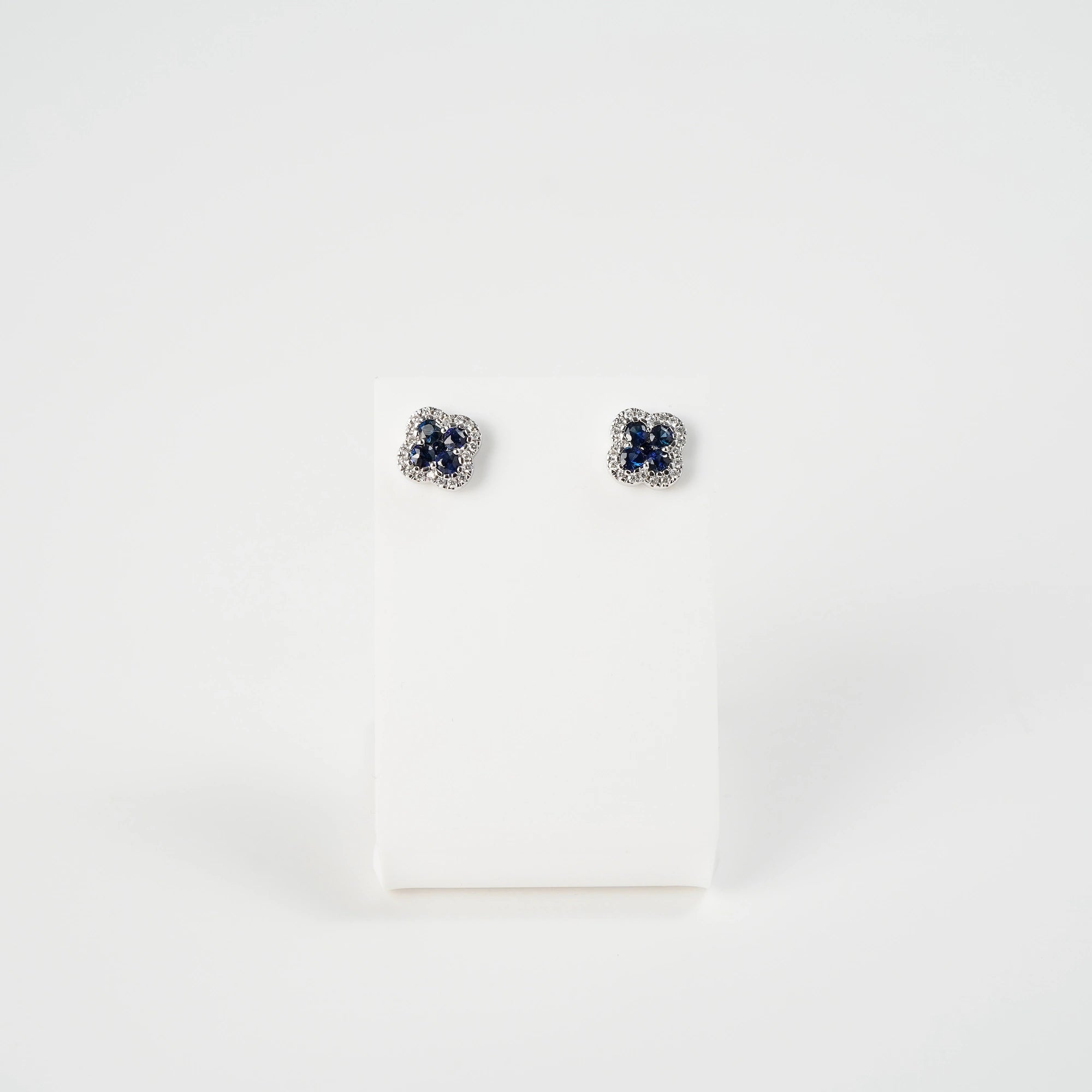 Die Schmuckatelier Lang Collection Ohrstecker im Saphir-Kleeblatt-Design werden auf einem entsprechenden Ständer präsentiert