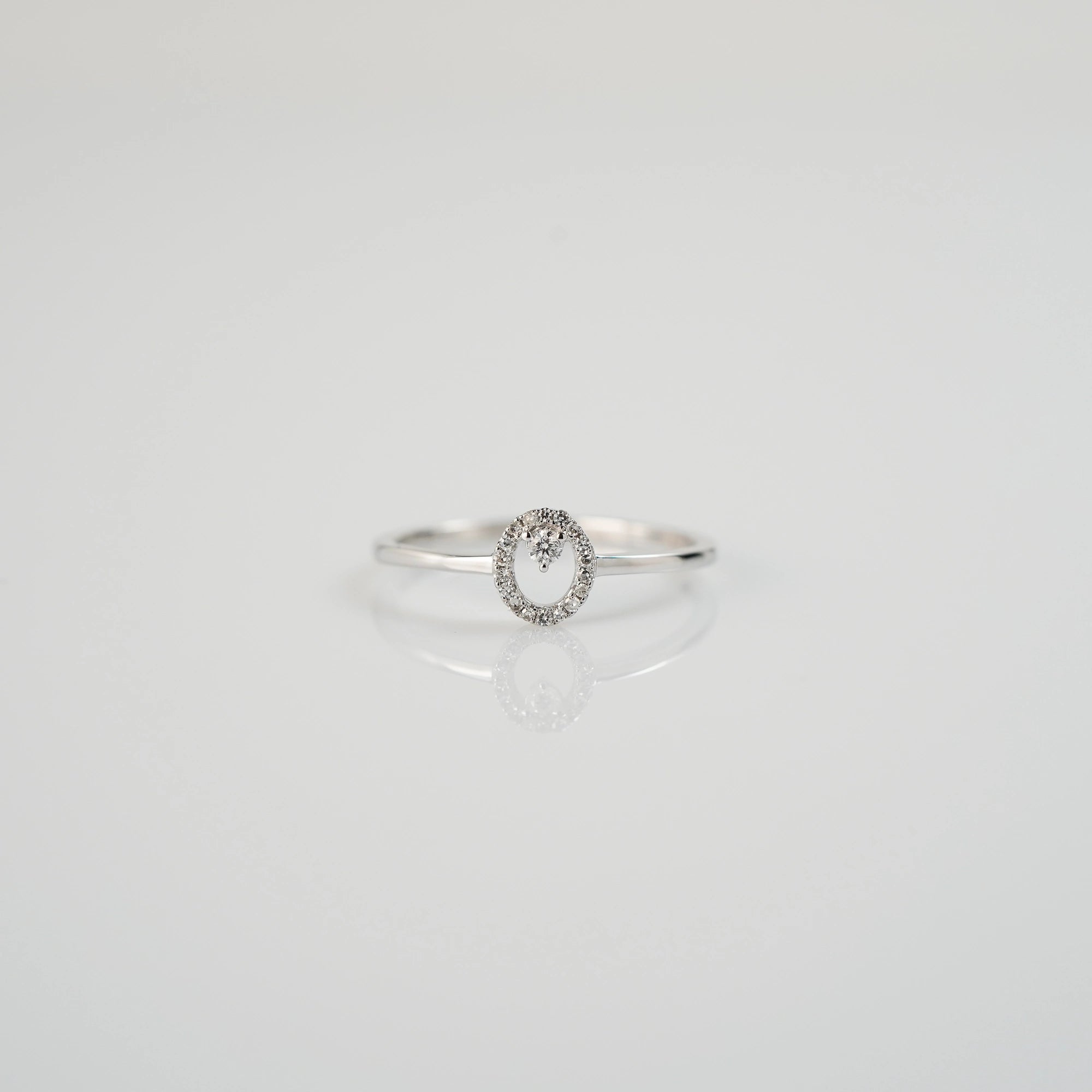 Produktfotografie des liegenden "Fine Oval" Verlobungsrings aus Weißgold, der mit einem ovalen Diamantkranz verziert wurde