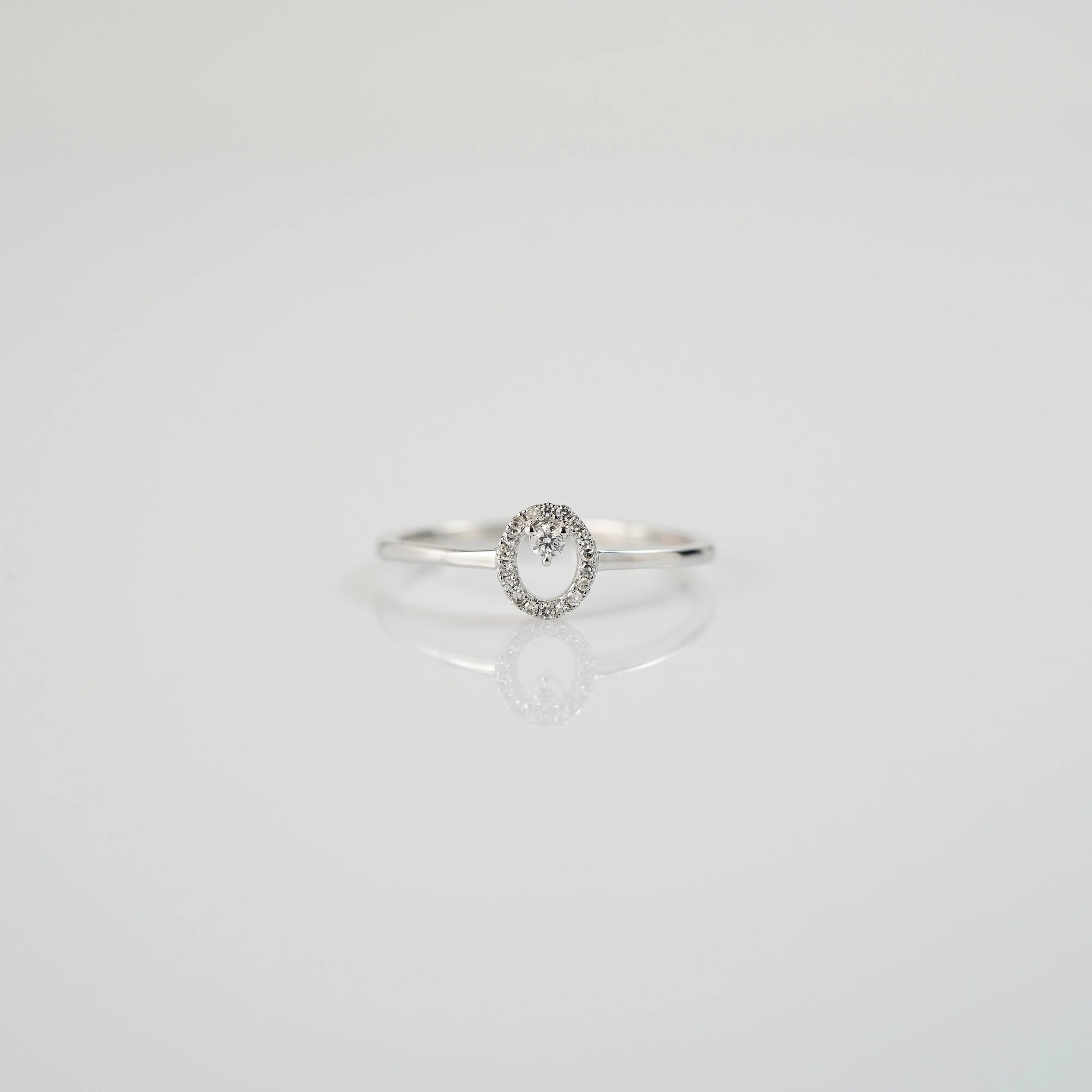 Produktfotografie des liegenden "Fine Oval" Verlobungsrings aus Weißgold, der mit einem ovalen Diamantkranz verziert wurde