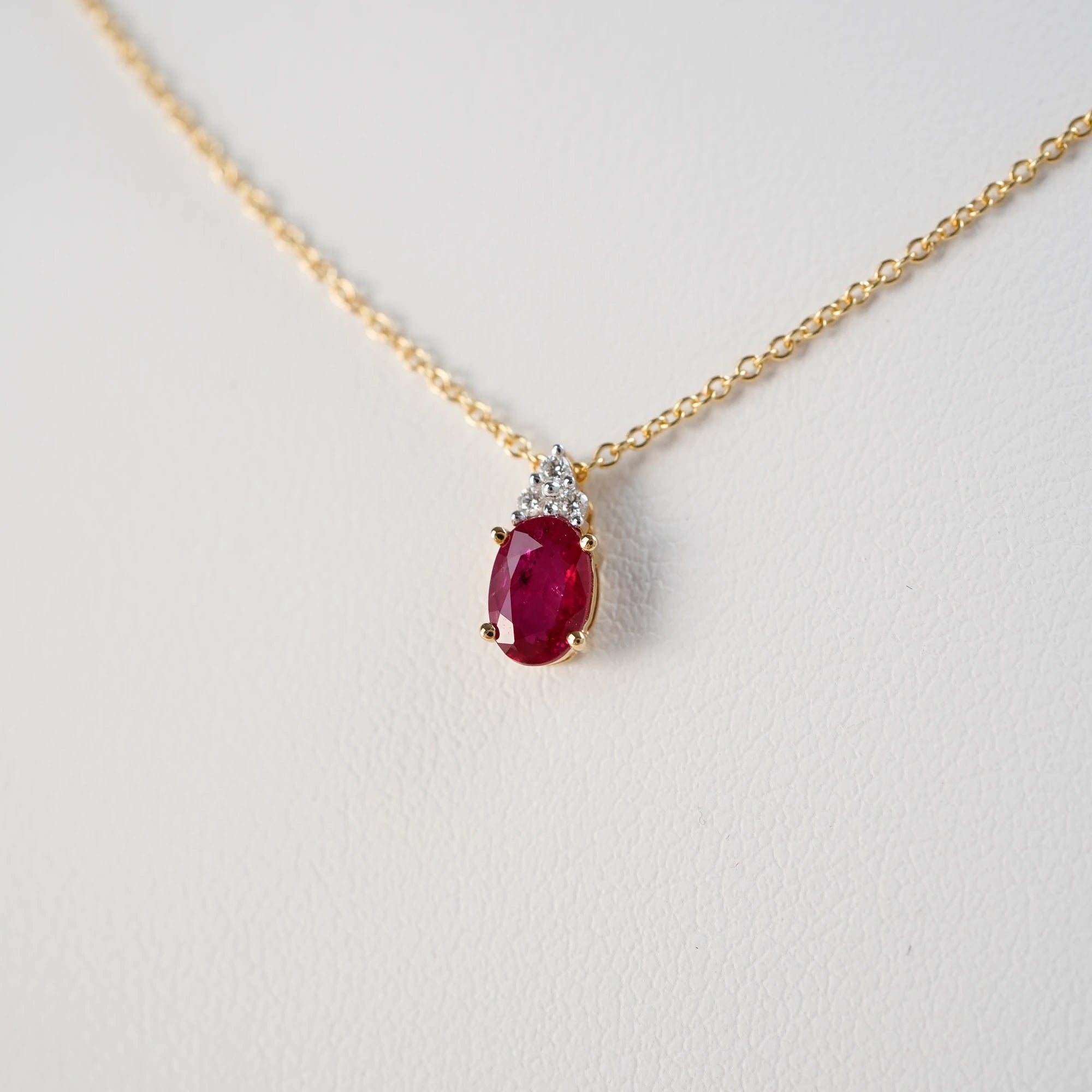 Detailaufnahme des Rubin Colliers aus der Schmuckatelier Lang Collection an einer gelbgoldenen Kette und einem mit Diamant-verzierten, ovalen Rubin-Anhängers