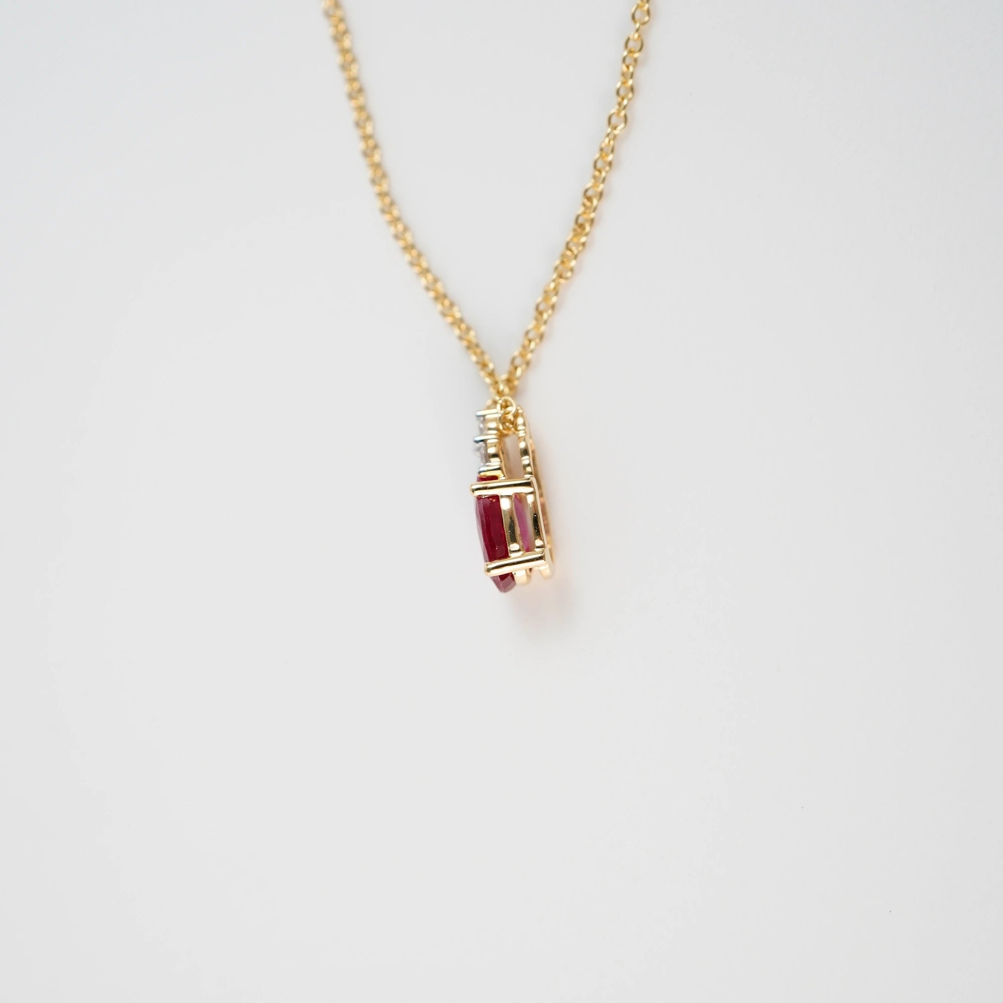 Seitliche Ansicht des Rubin Colliers aus der Schmuckatelier Lang Collection an einer gelbgoldenen Kette und einem mit Diamant-verzierten, ovalen Rubin-Anhängers