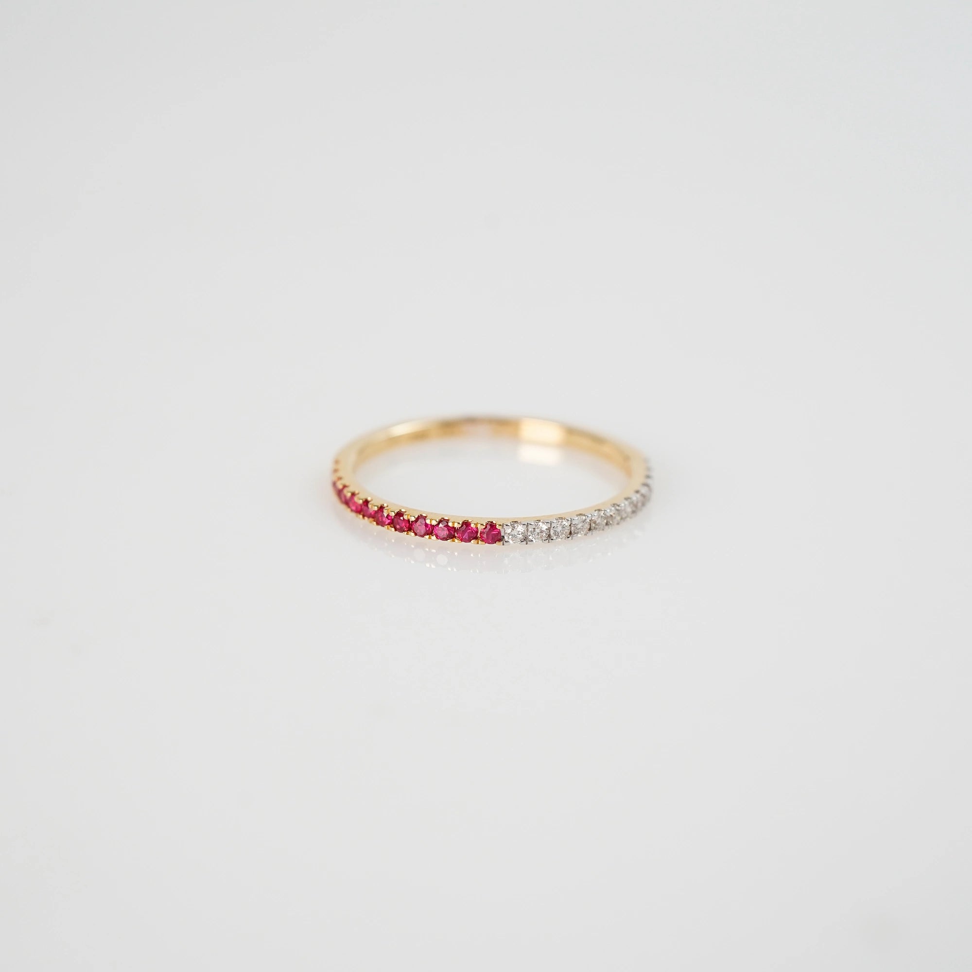 Produktfoto des liegenden Memoire Rings aus der Schmuckatelier Lang Collection, der halb mit Rubinen und halb mit Diamanten besetzt ist 