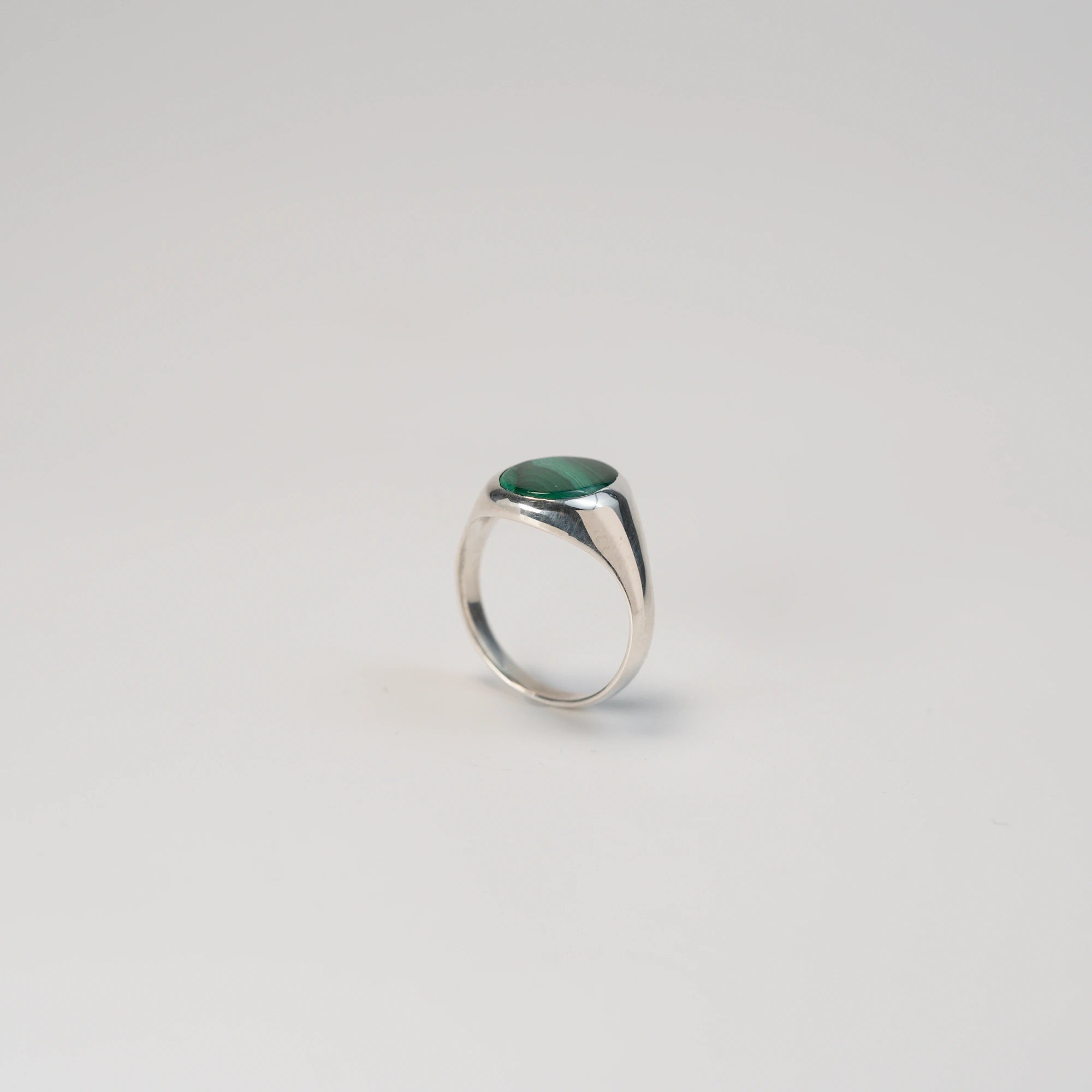 Seitliche Ansicht des stehenden, handgefertigten Siegelrings aus 925er Silber mit einem eingefassten, ovalen Malachit Edelstein