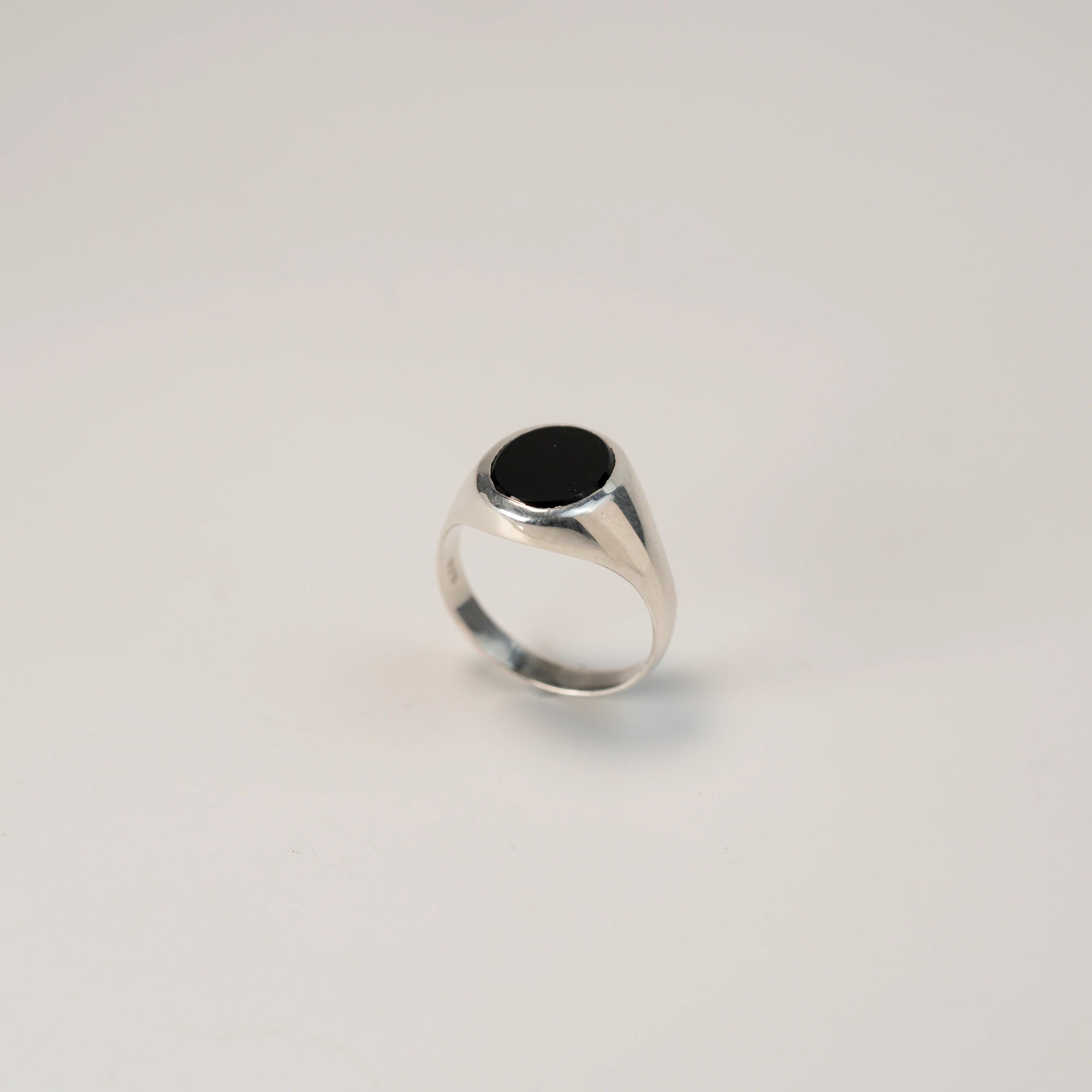 Seitliche Ansicht des stehenden, handgefertigten Siegelrings aus 925er Silber mit einem eingefassten, ovalen Onyx Edelstein