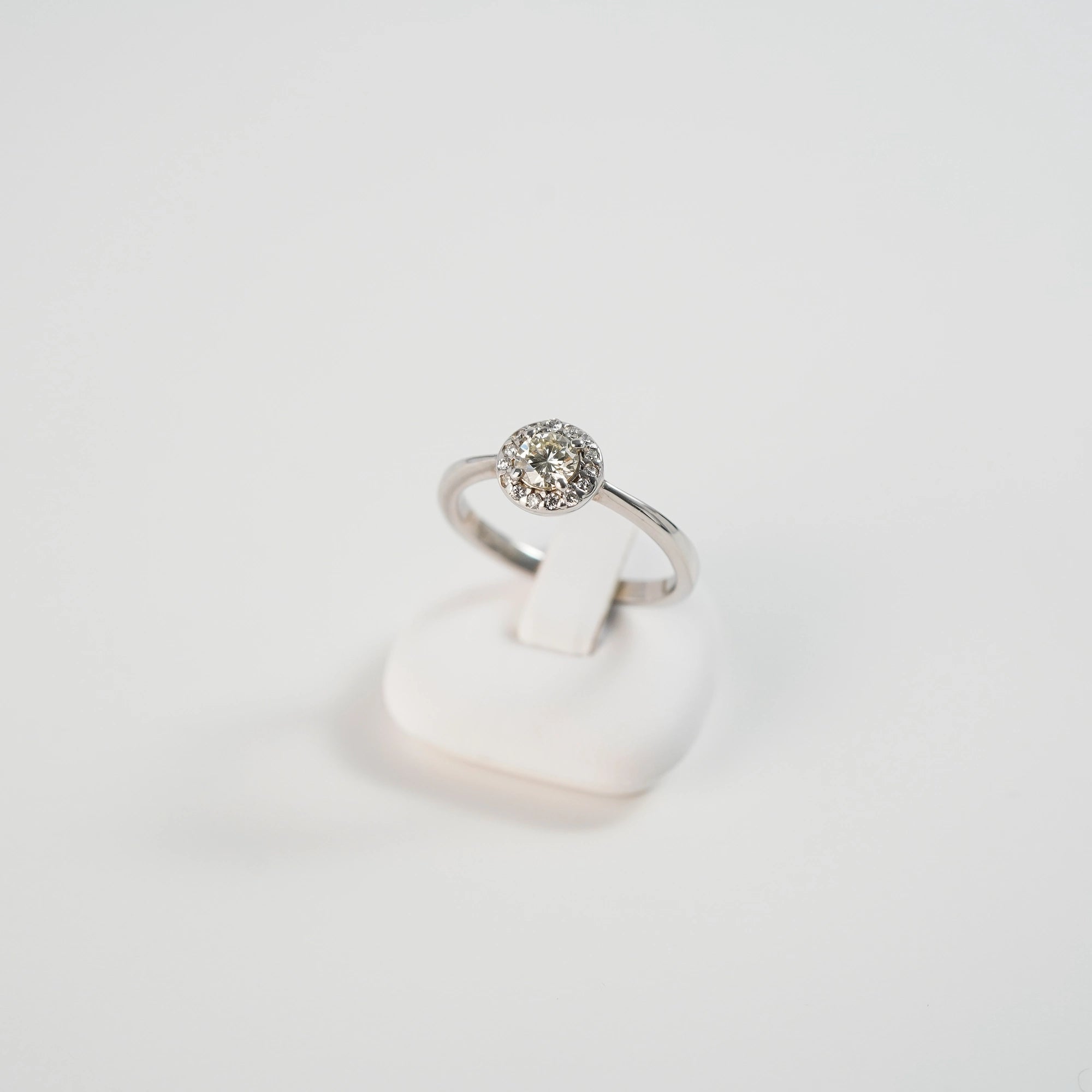 Produktfoto des Verlobungsrings "Blossom" aus der Schmuckatelier Lang Collection in Weißgold mit einem markantem Detail aus mehreren Diamanten, dass in der Anordnung an eine Blüte erinnert, währrend dieser auf einem Ringständer steckt