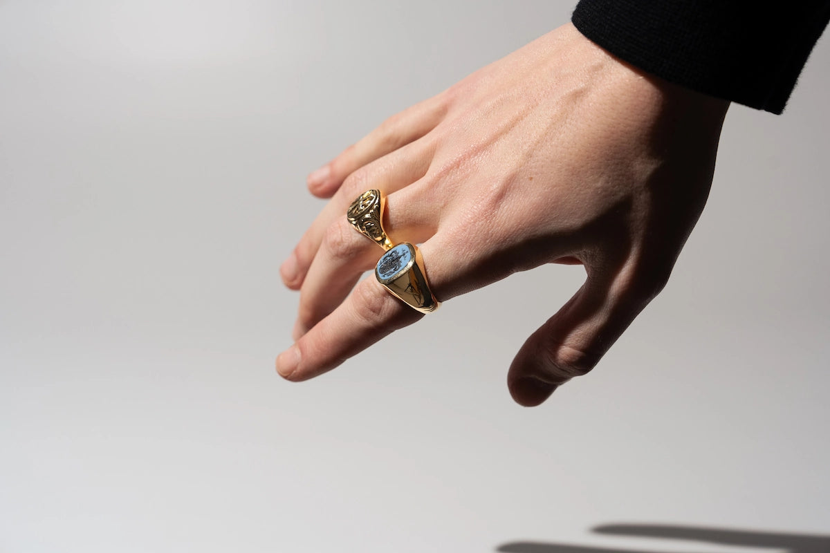 Mann trägt zwei Siegelringe aus Gold an seinem Zeige- und Mittelfinger