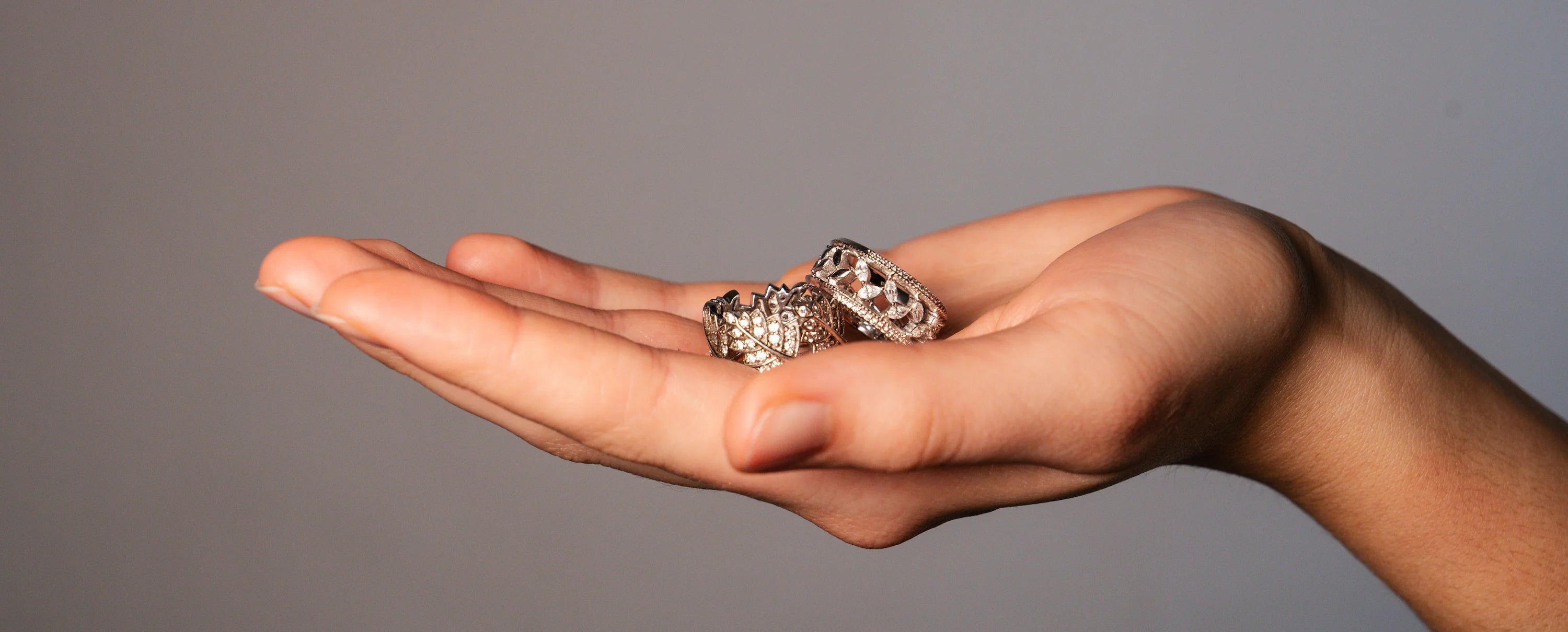 Frau hält zwei Ringe in Ihrer Handfläche und präsentiert die silbernen Modeschmuck-Ringe mit Zirkonia-Besatz