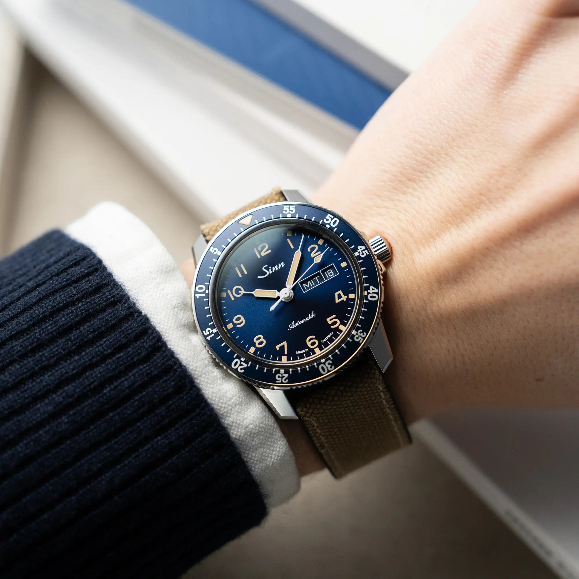 Mann trägt die Taucheruhr Sinn Automatik SA in Blau mit beigen Akzenten am Textilband an seinem Handgelenk