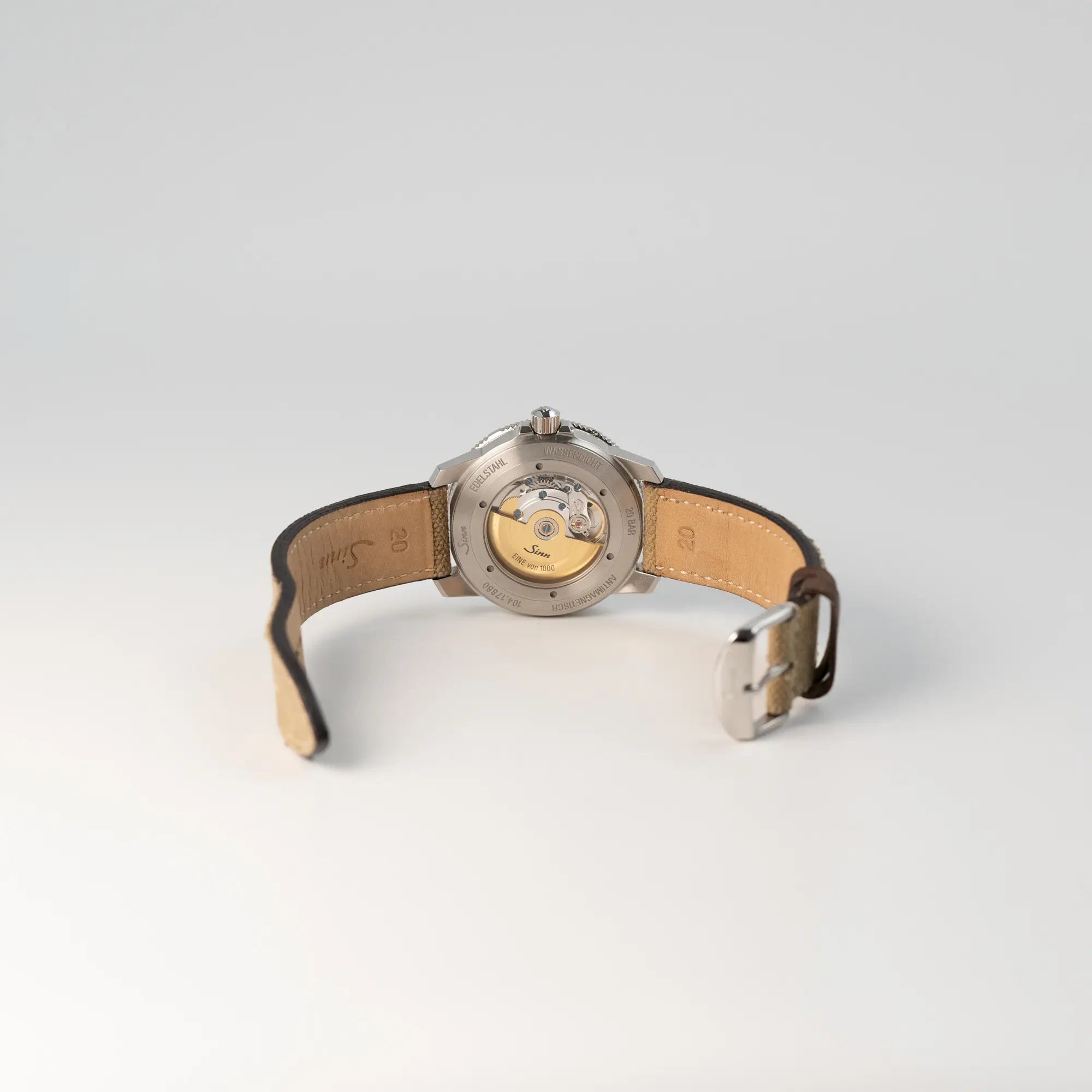 Blick auf den gläsernen Gehäuseboden und die geöffnete Dornschliesse der Sinn Automatik SA Taucheruhr in Blau mit beigen Akzenten am Textilband