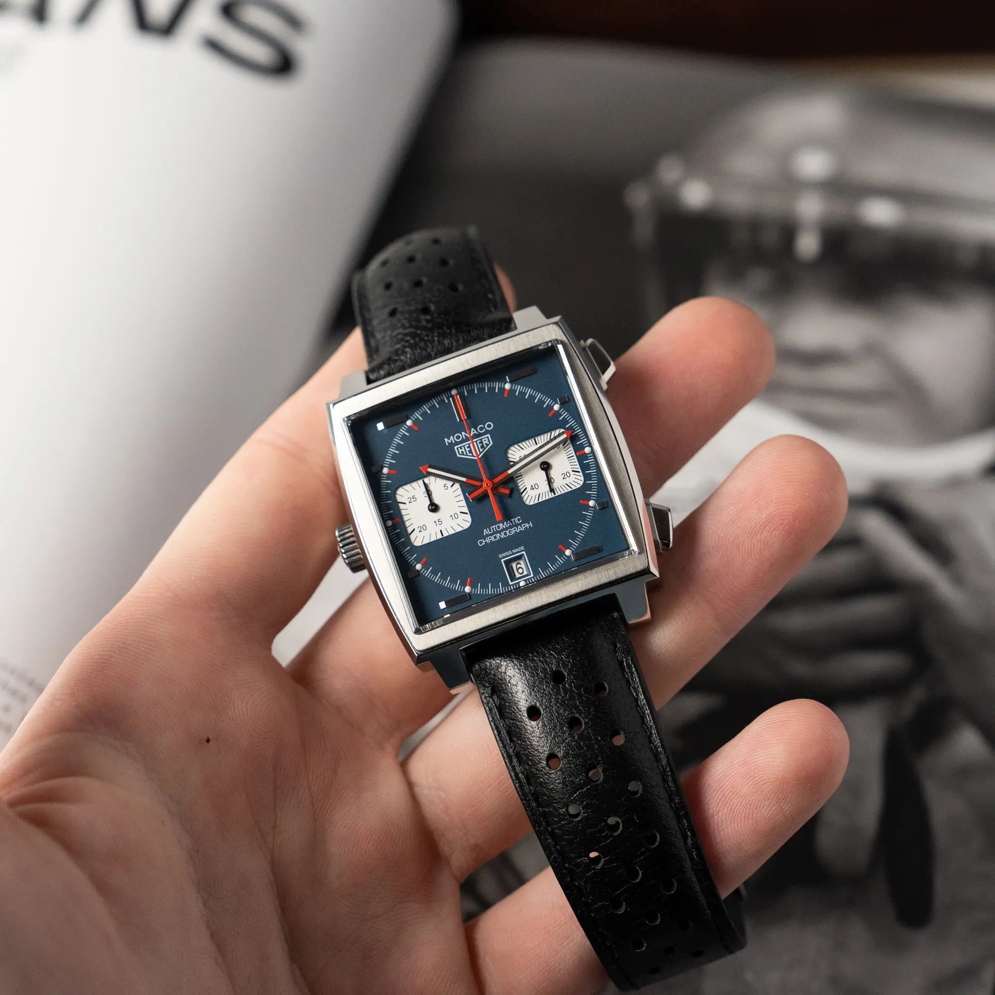 Mann hält den Tag Heuer Monaco Calibre 11 Chronographen CAW211P mit dem klassischen blauen Zifferblatt und roten Details auf Zeigern und Indizes in seiner Hand