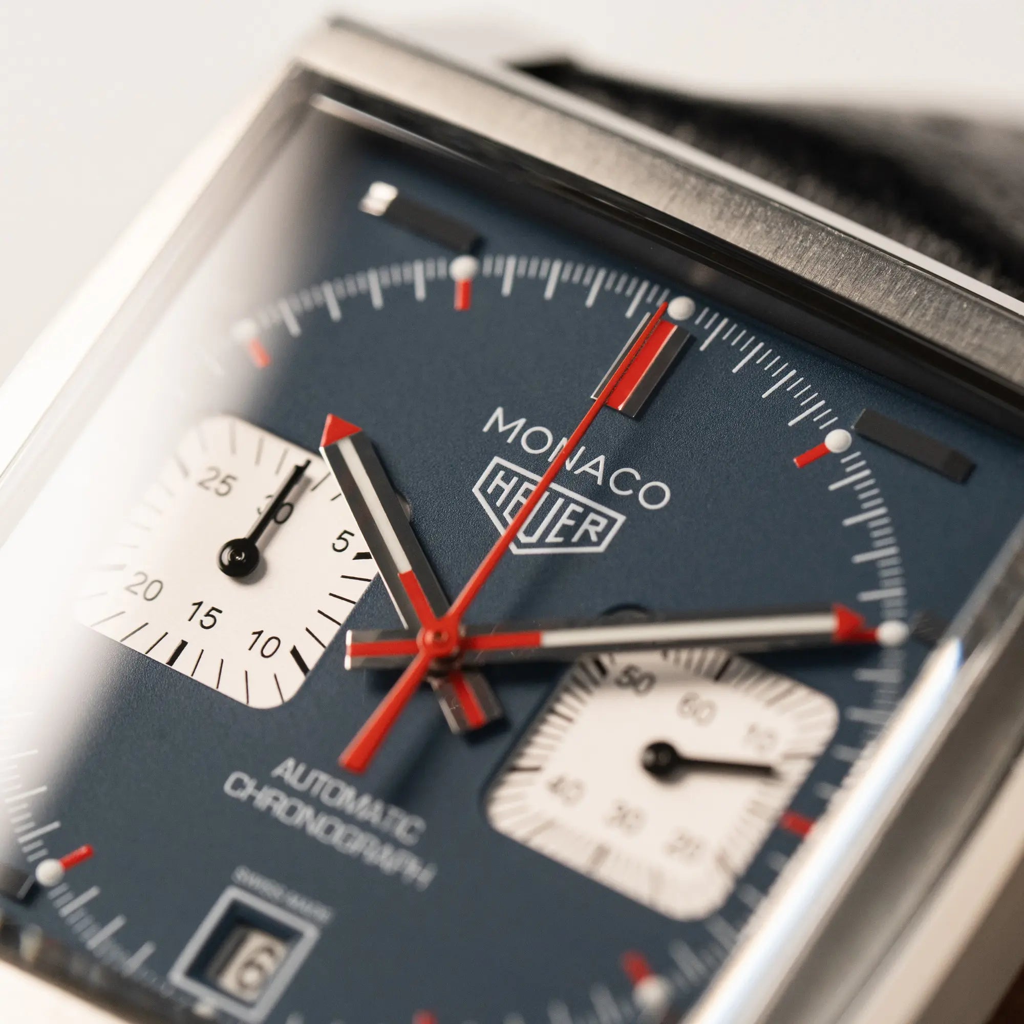 Detailaufnahme des Tag Heuer Monaco Calibre 11 Chronographen CAW211P mit dem klassischen blauen Zifferblatt und roten Details auf Ziegern und Indizes mit Fokus auf dem Zeigersatz