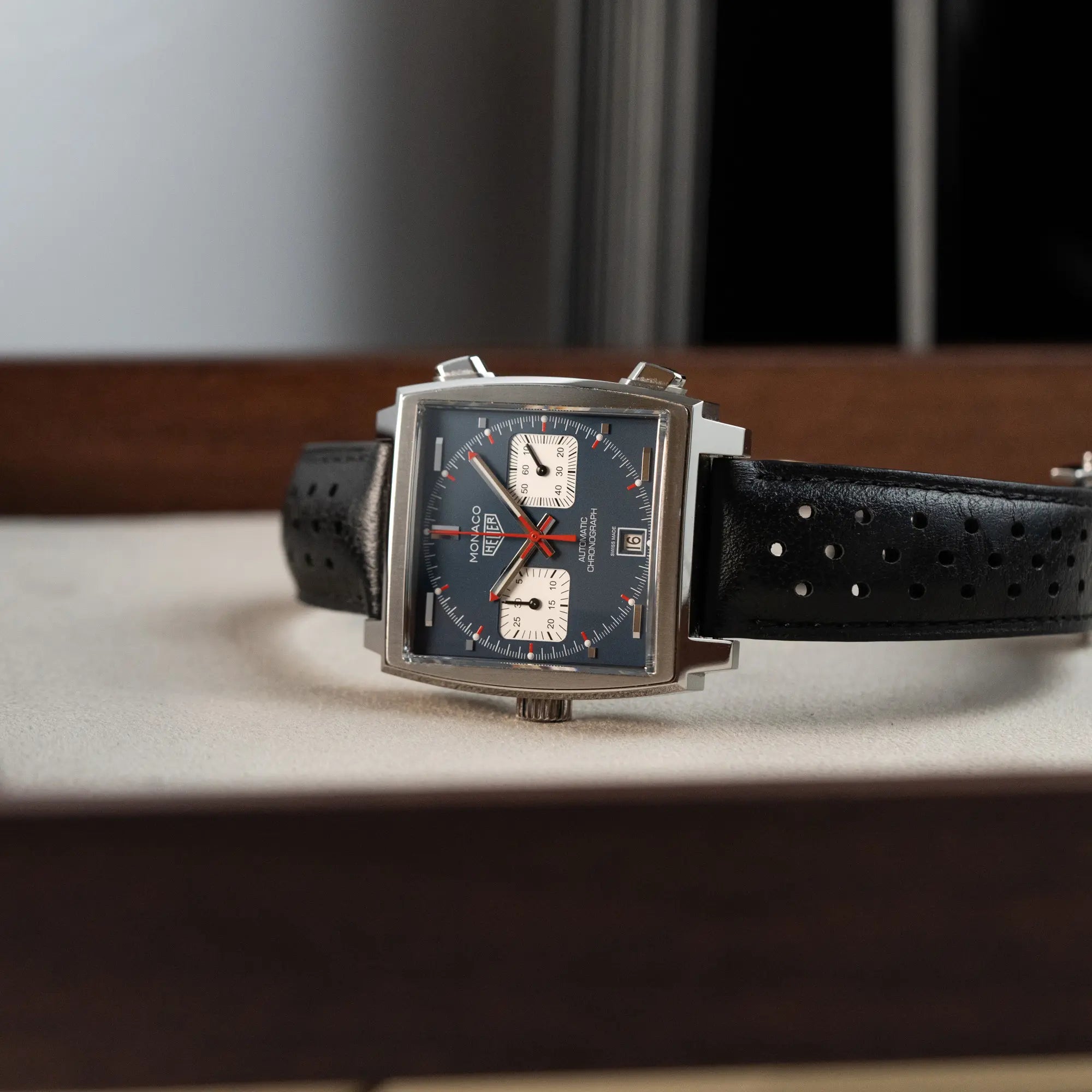 Produktfotografie des Tag Heuer Monaco Calibre 11 Chronographen CAW211P mit dem klassischen blauen Zifferblatt und roten Details auf Zeigern und Indizes