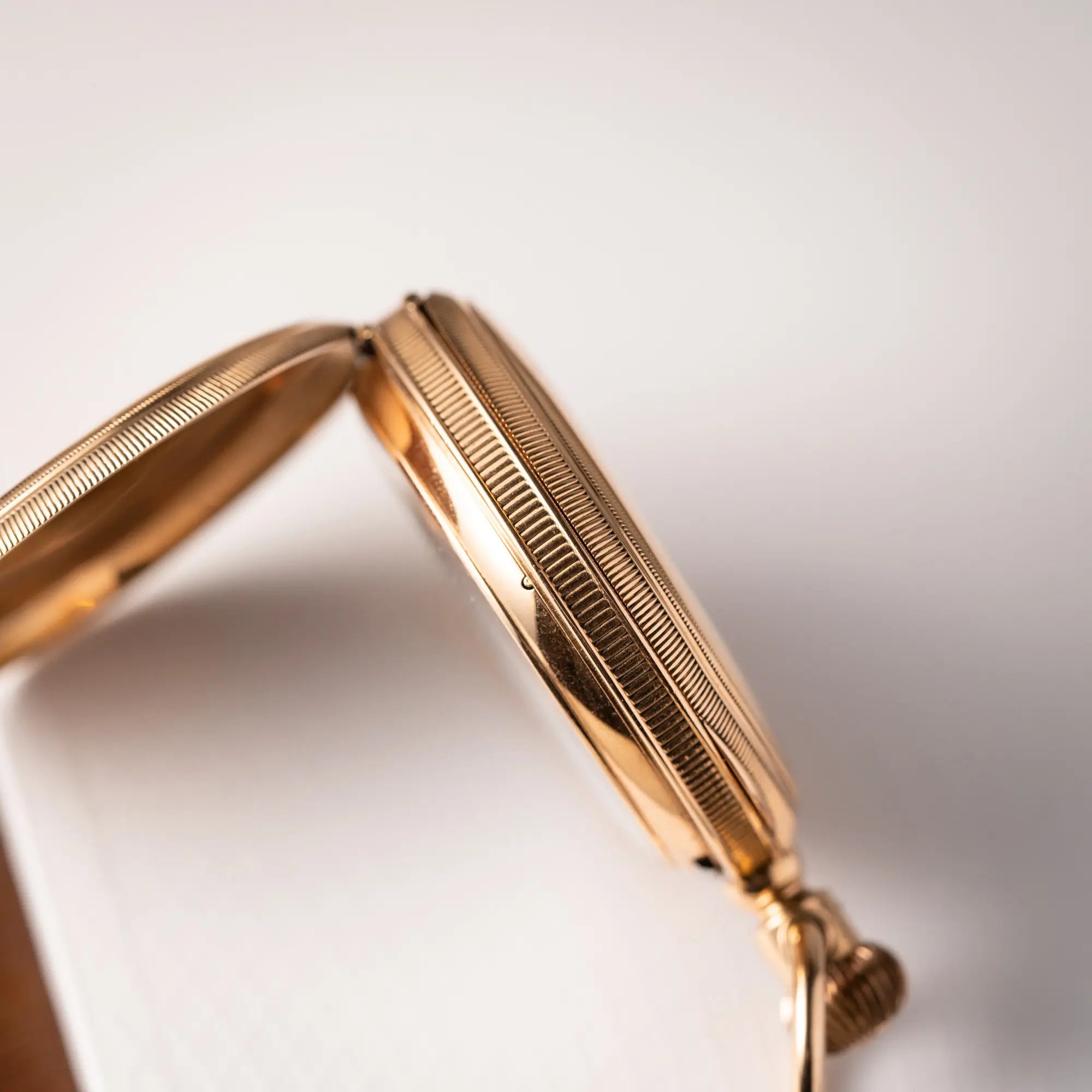 Produktfotografie der Tiffany & Co Savonette Taschenuhr aus 18k Gelbgold mit weißem Zifferblatt und römischen Indizes zeigt die seitliche Gehäuseflanke mit Kannelierung