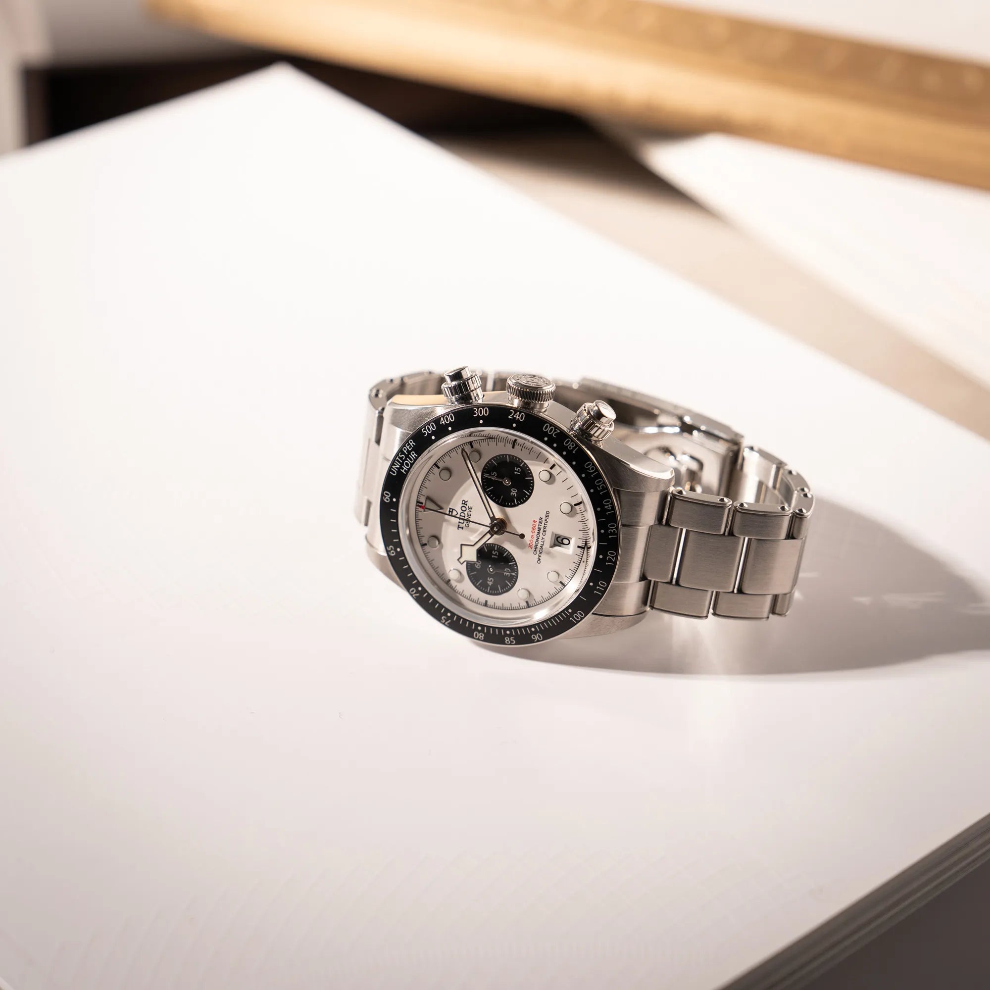 Tudor Black Bay Chronograph 79360N mit dem Panda-Zifferblatt in weiß mit schwarzen Totalisatoren liegt auf der seitlichen Gehäuseflanke für ein Produktfoto
