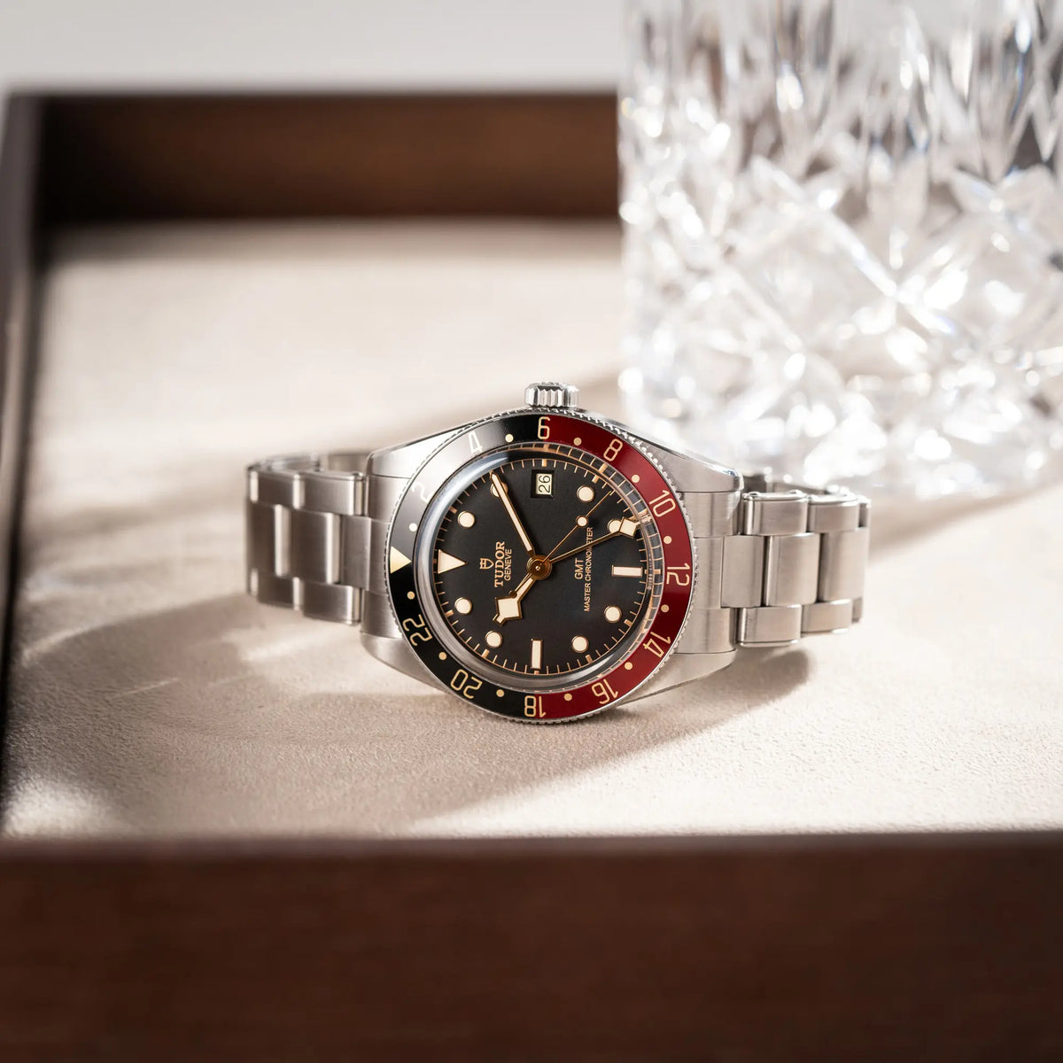 Tudor BlackBay GMT Coke der Referenz 7939G1A0NRU mit der schwarz-roten Lünette und bronzefarbenen Details am Edelstahlarmband liegt auf einem Juwelierstablet