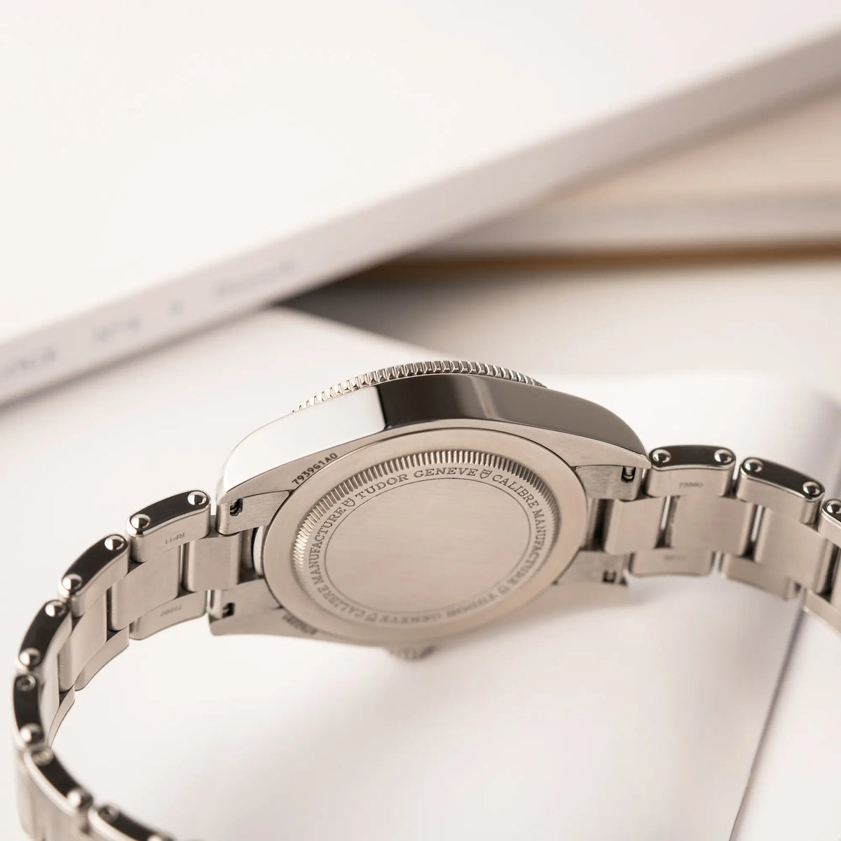Produktfotografie zeigt die seitliche Gehäuseflanke der Tudor BlackBay GMT Coke der Referenz 7939G1A0NRU mit der schwarz-roten Lünette und bronzefarbenen Details am Edelstahlarmband