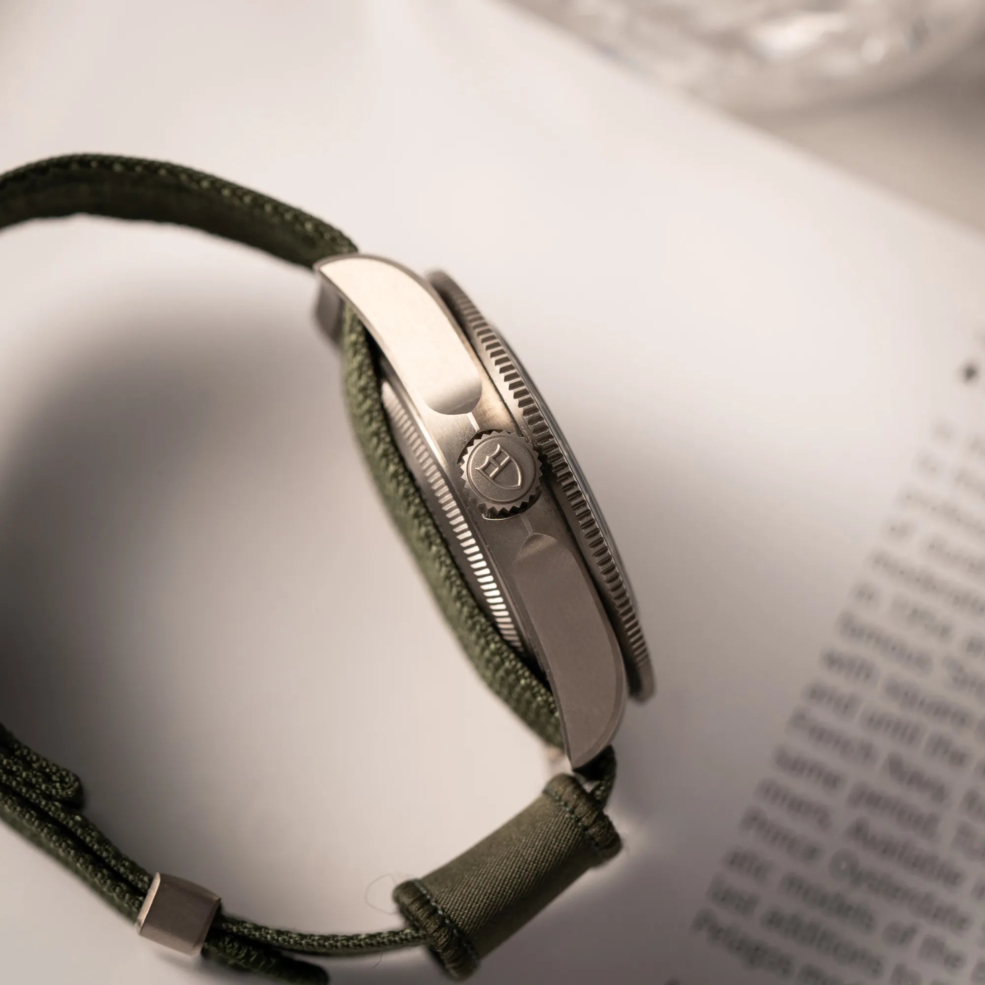 Seitliche Gehäuseflanke mit Blick auf die Aufzugskrone der Tudor Pelagos GMT Military der Referenz M2542G257NU-0002 mit Titan-Gehäuse und schwarzem Zifferblatt an einem olivgrünen Nato-Strap